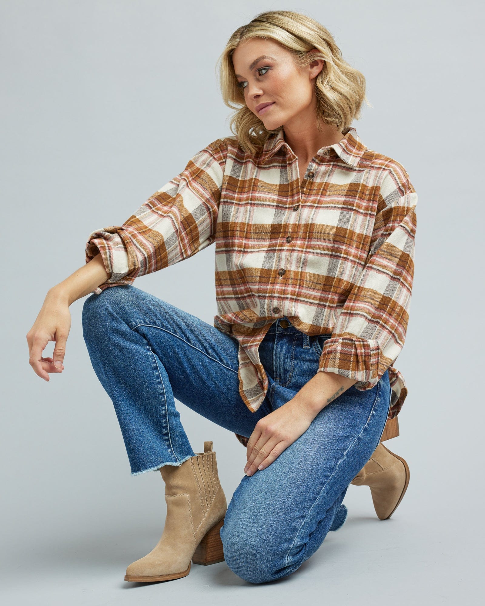 Woman in a long sleeve, tan and brown plaid, button-down blouse