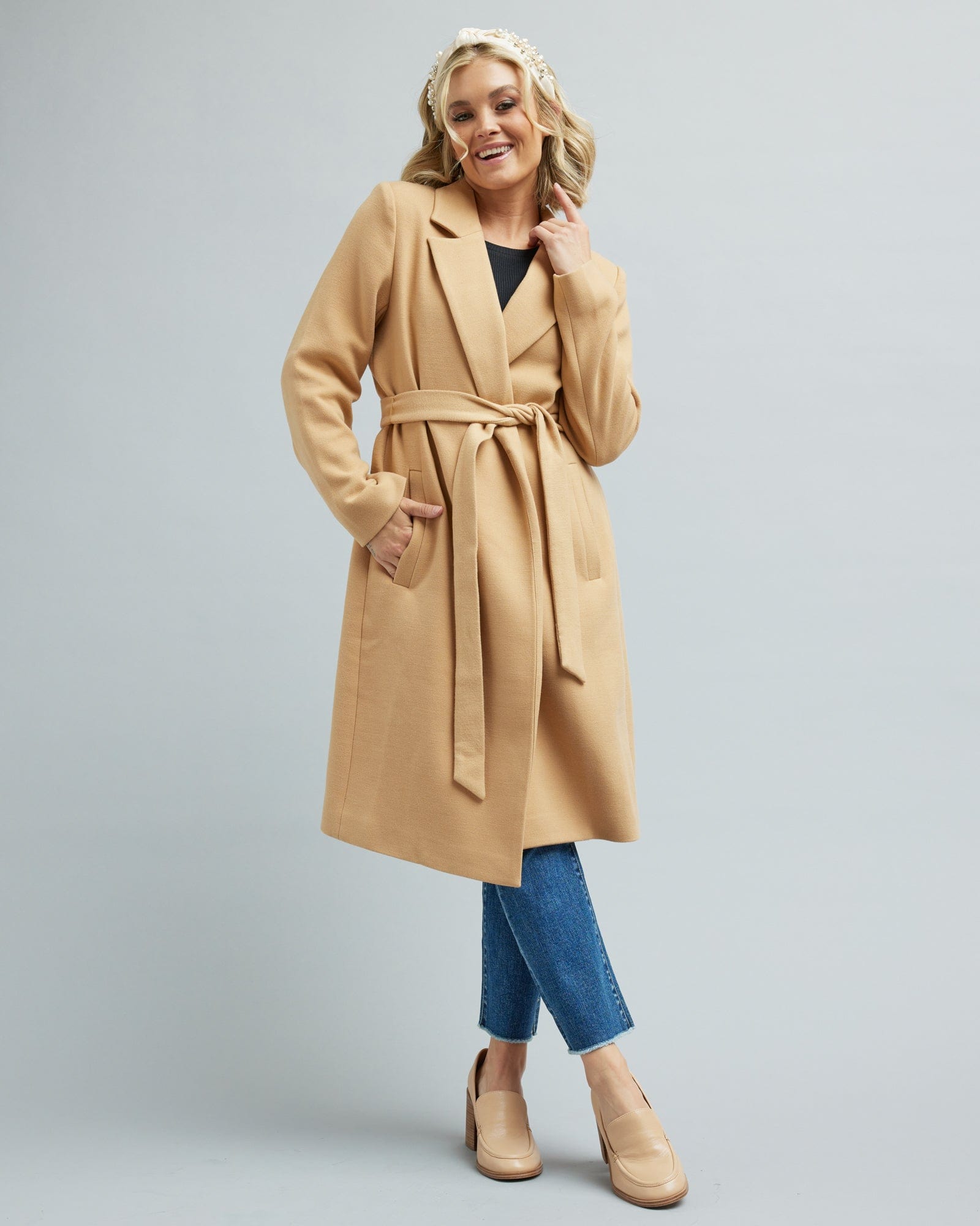 Woman in a tan color, long sleeve, belted coat