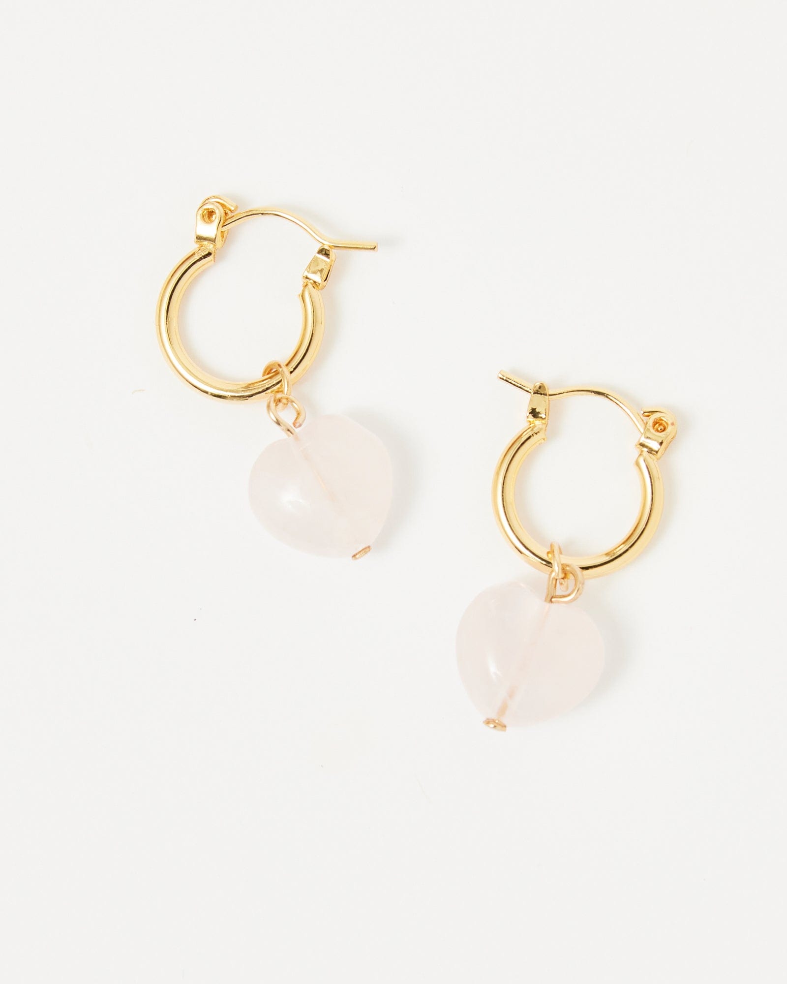 Gold huggie hoop earrings with heart shaped rose quartz bead on end.