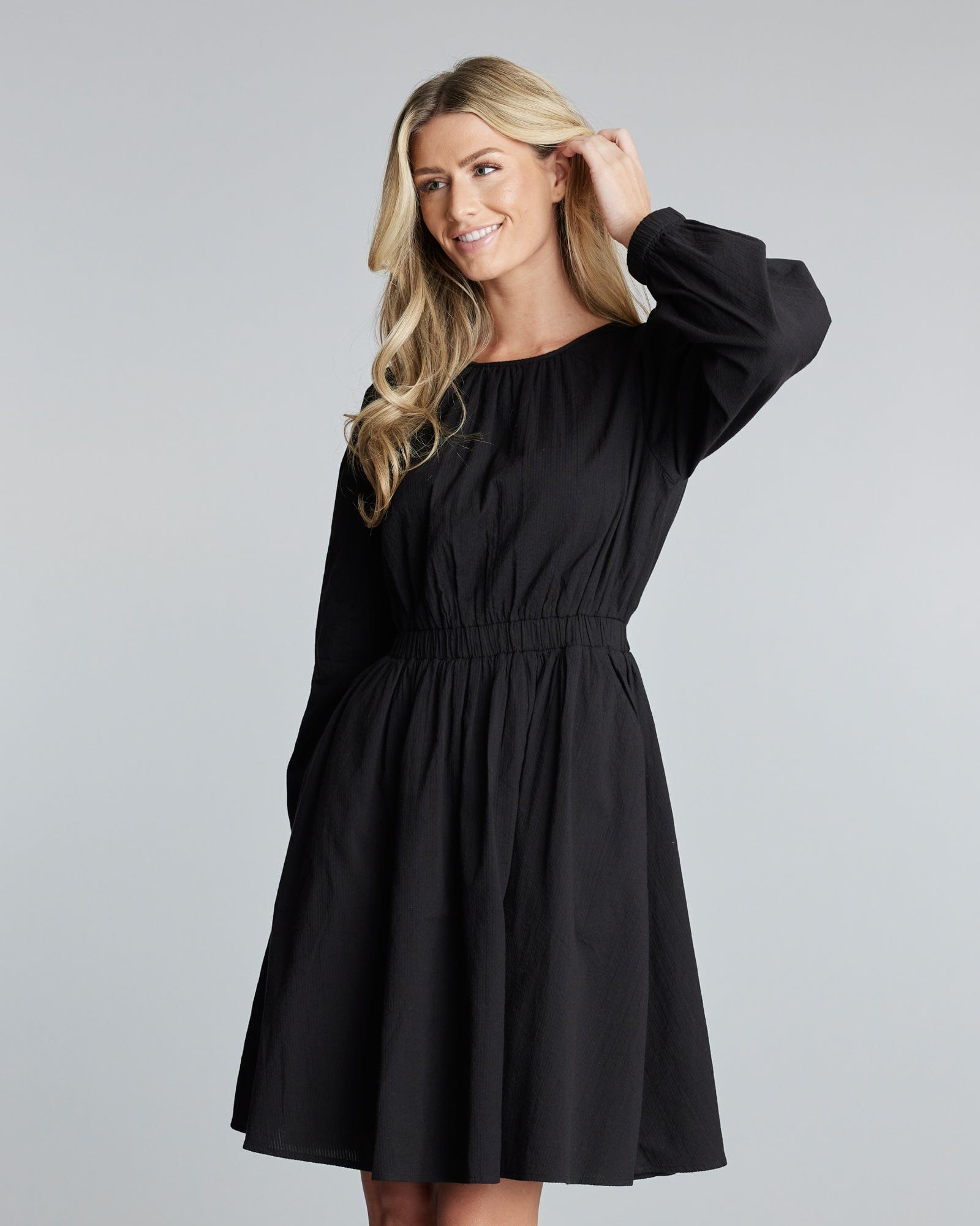 Woman in a black long sleeve, knee-length dress.