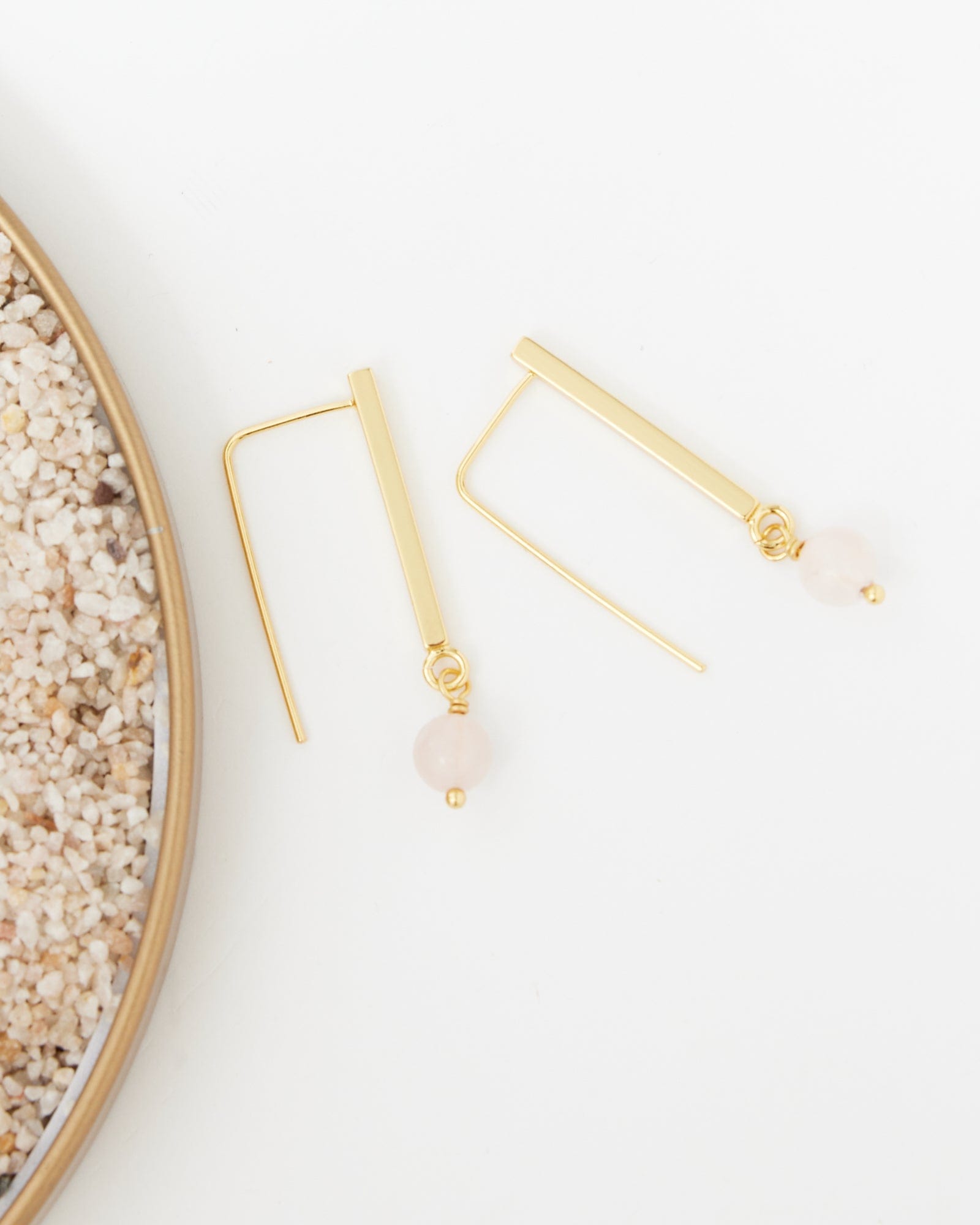 Two gold earrings with small pink bead at end