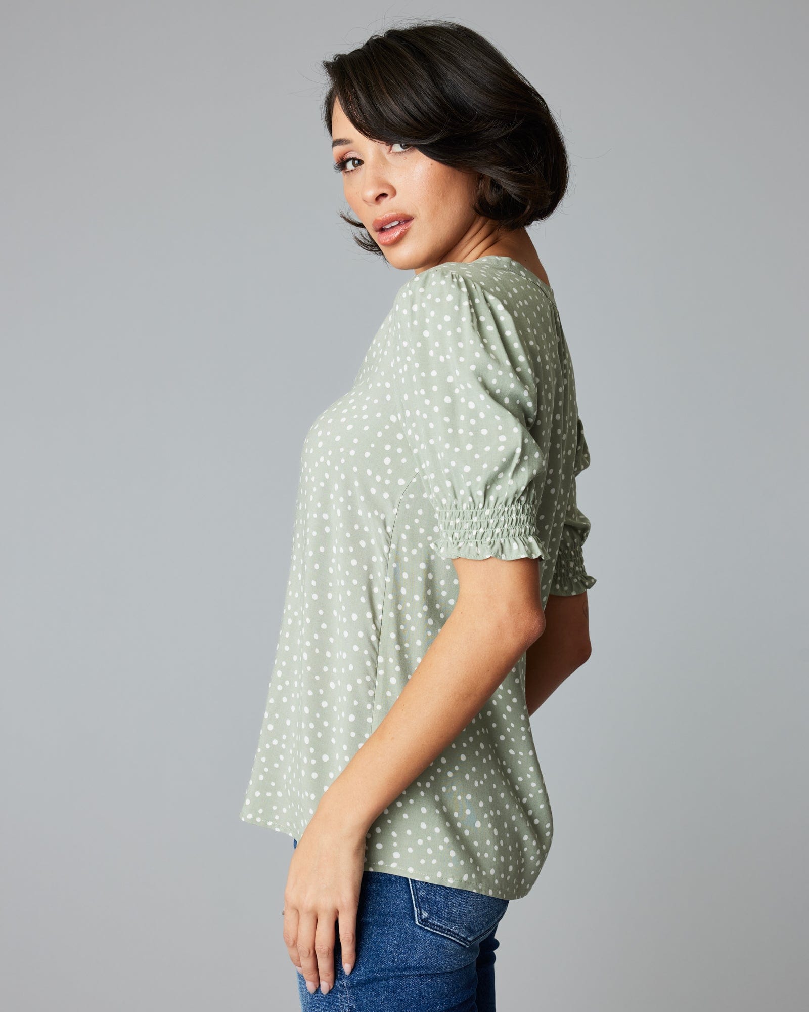 Woman in a short sleeve, green, polka dotted blouse.