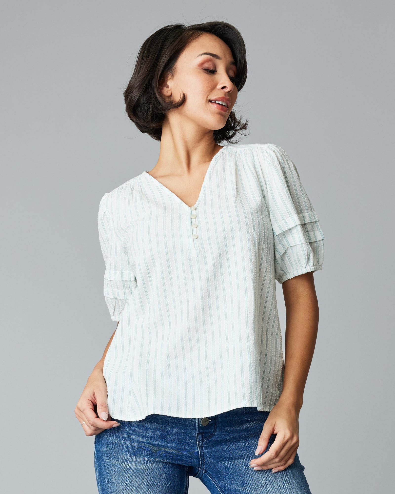 Woman in a short sleeve, v-neck, white and green vertical striped blouse.