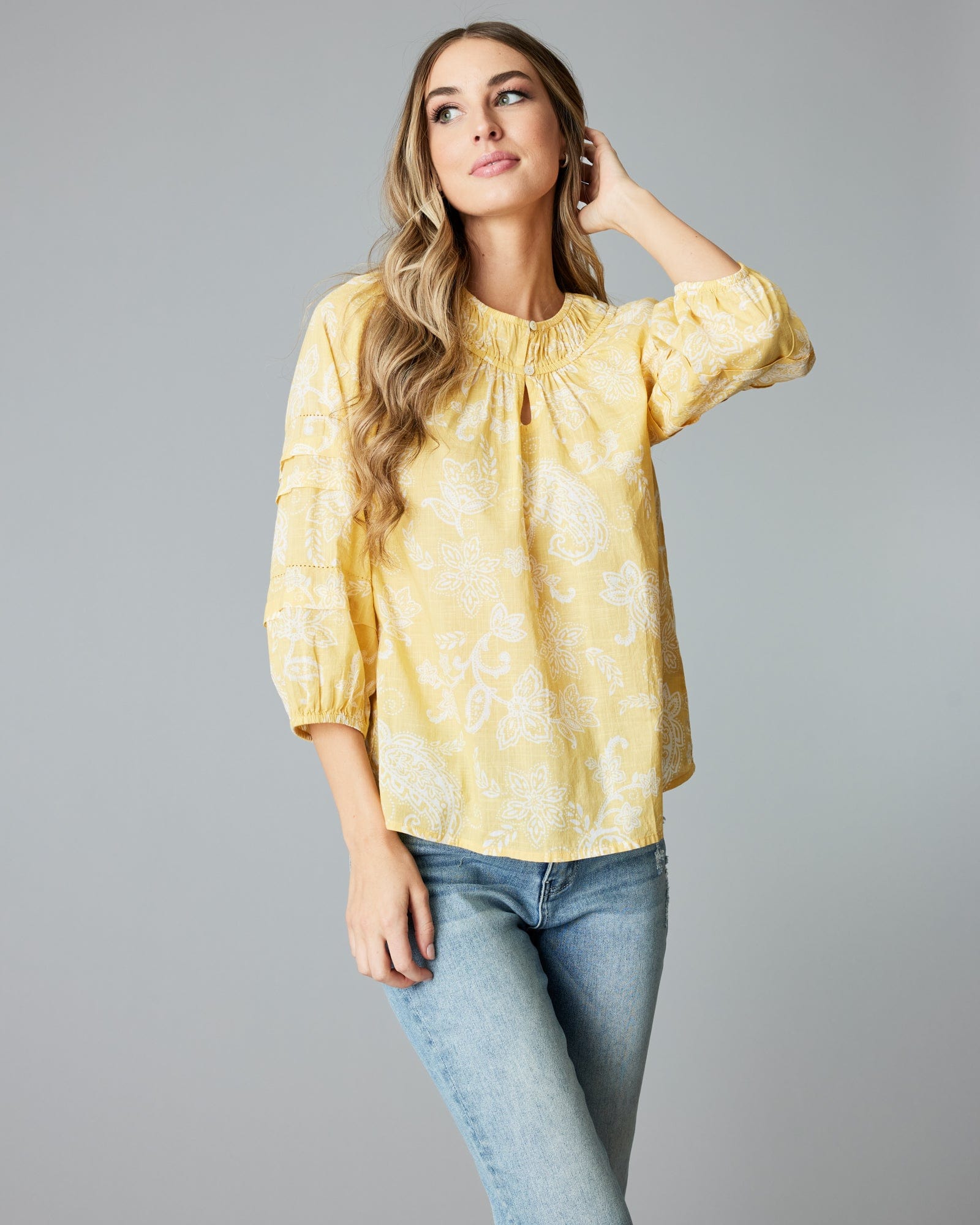 Woman in a 3/4 sleeve, yellow blouse.