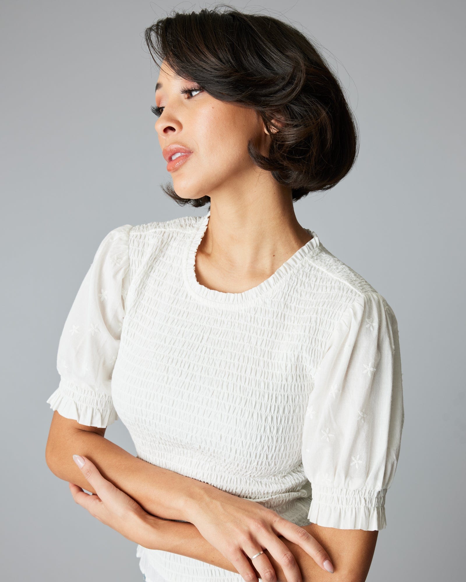 Woman in a short sleeved, smocked, white blouse.