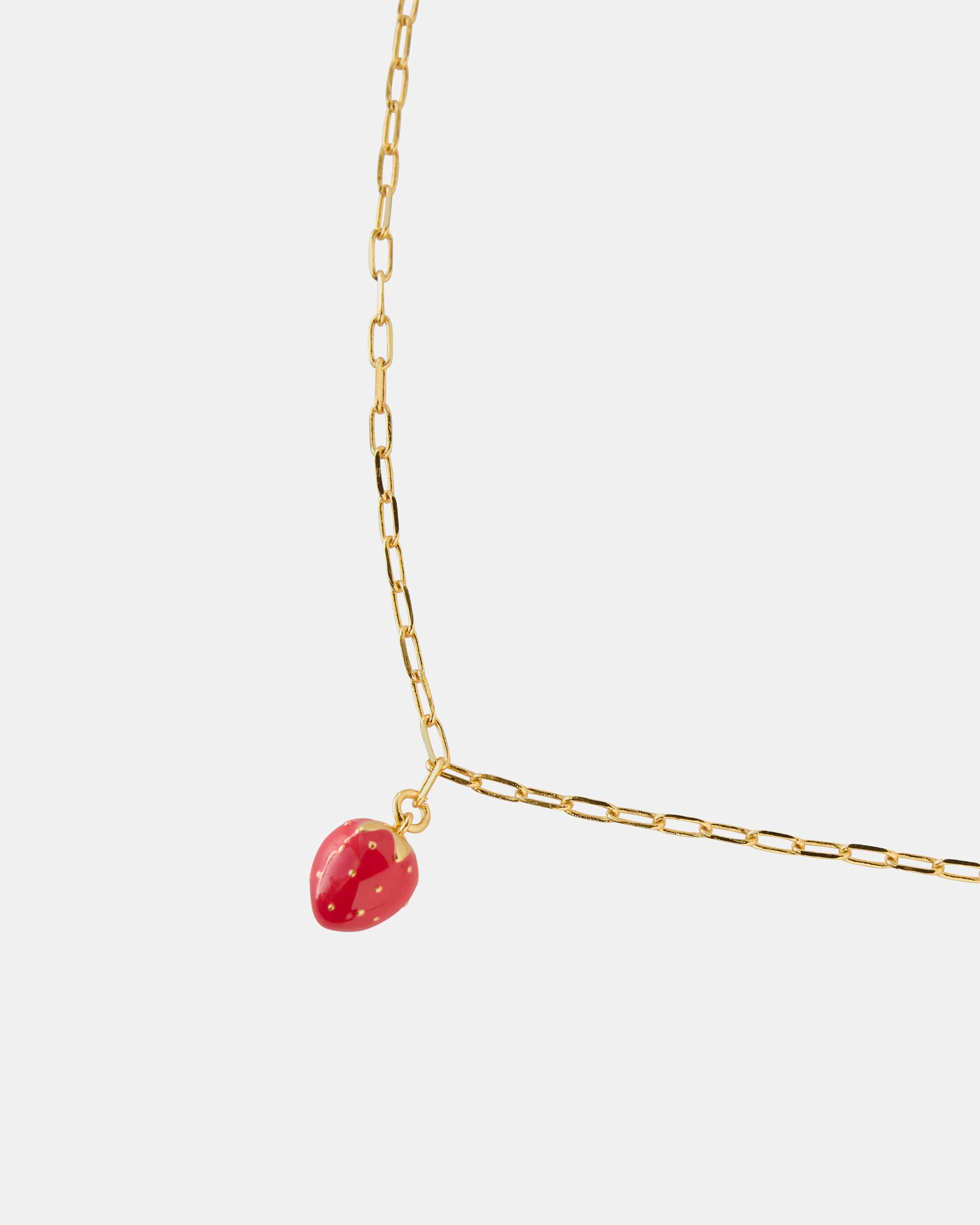 Gold necklace with a red strawberry charm.