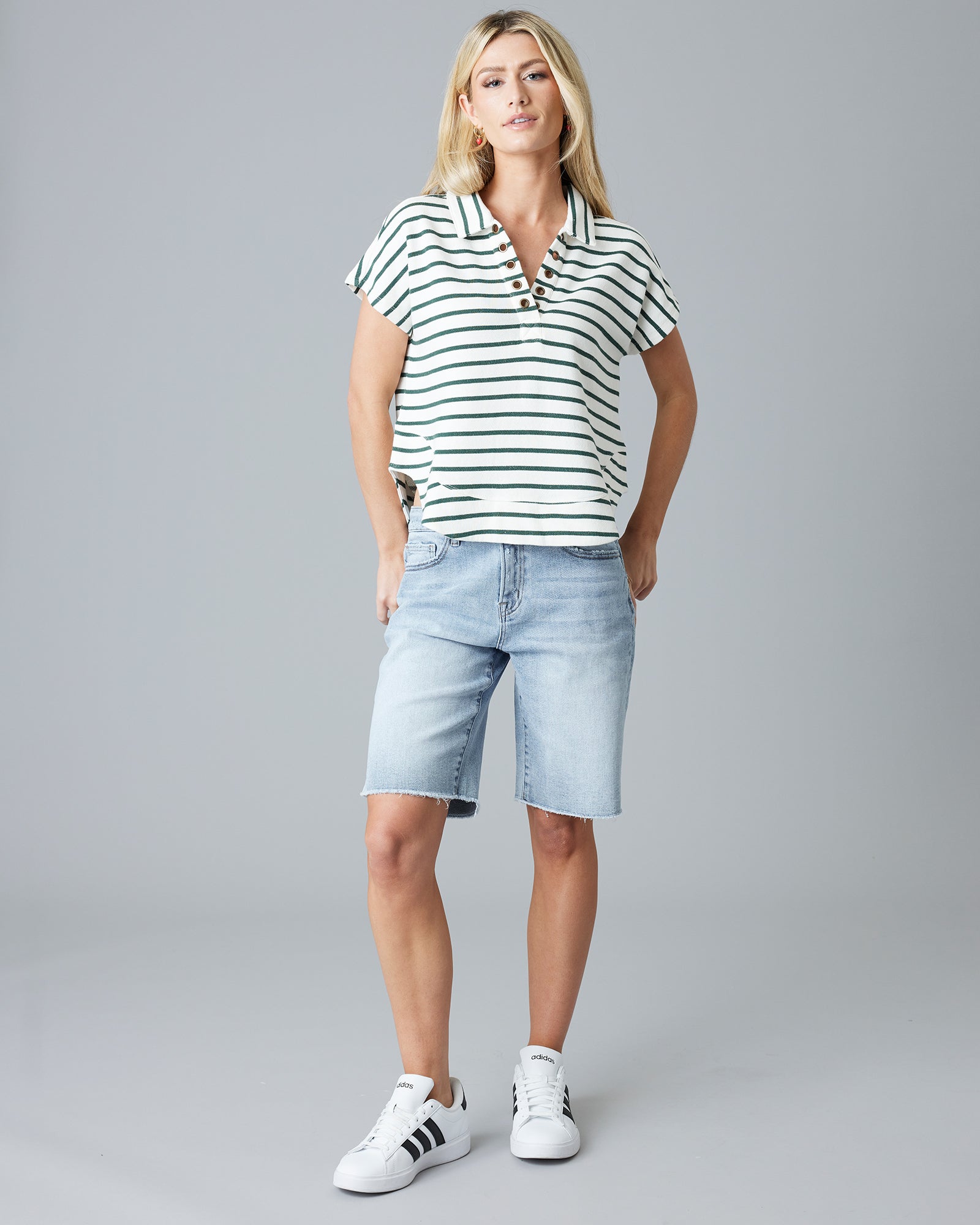 Woman in a green and white striped, short sleeve, v-neck with collar sweater