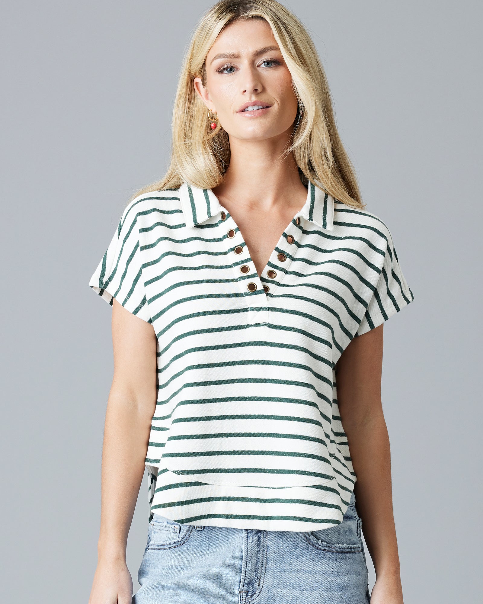 Woman in a green and white striped, short sleeve, v-neck with collar sweater