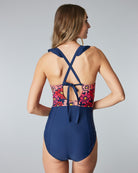 Woman in a one-piece swimsuit with pink flowers on the top and sold blue on the bottom.
