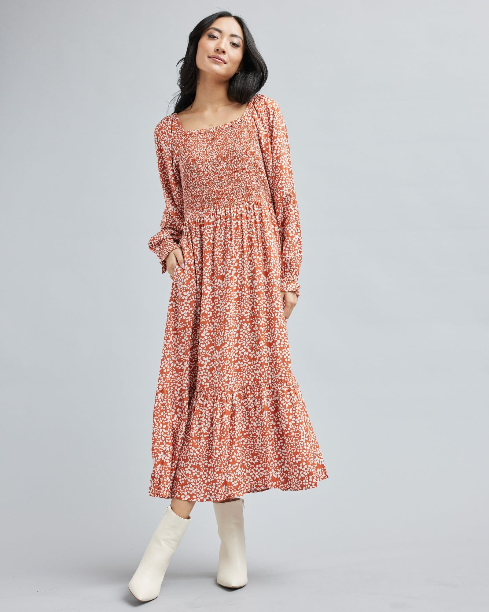 Woman in a long sleeve, midi-length, orange and white floral dress