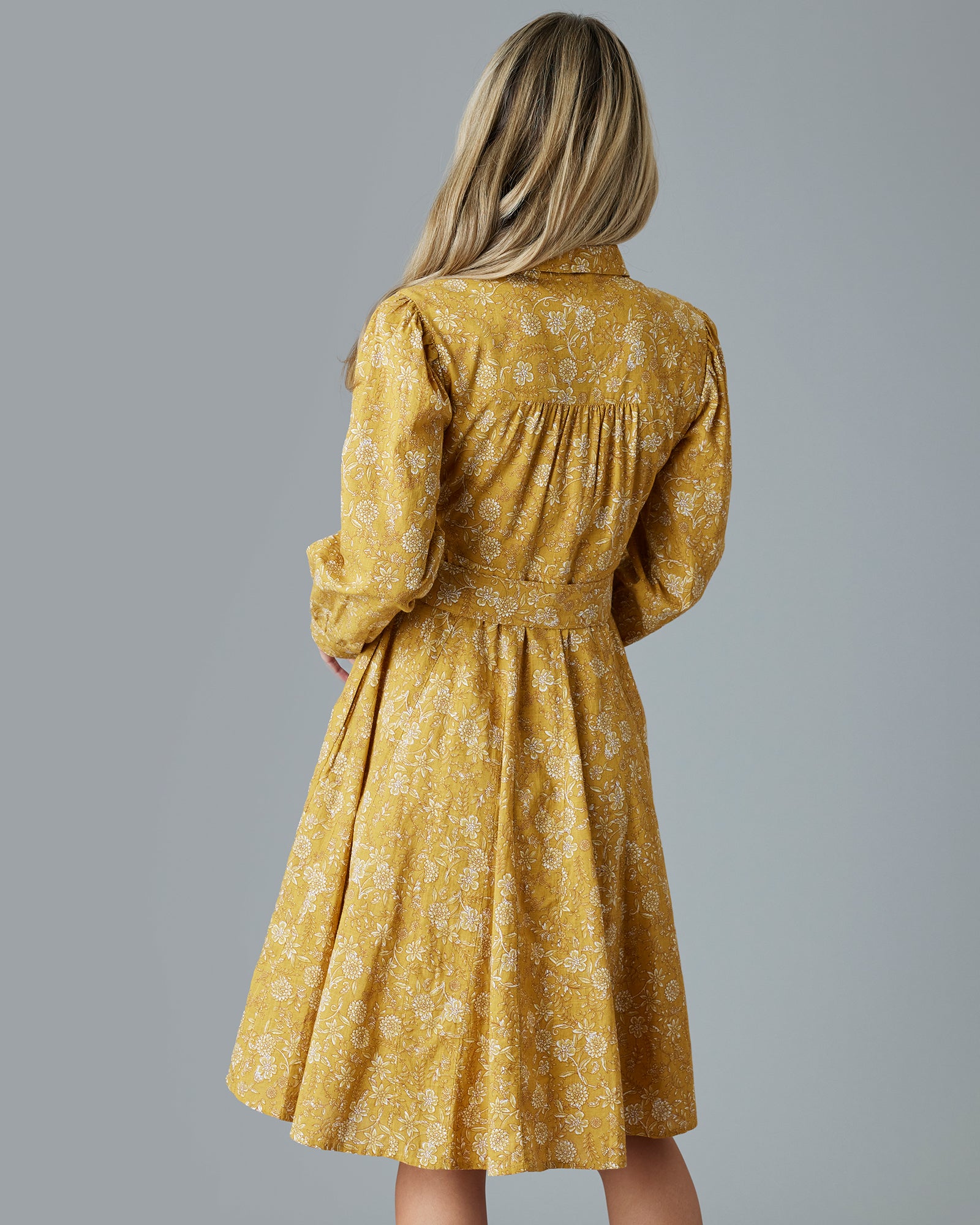 Woman in a long sleeve, collared, knee-length, yellow dress