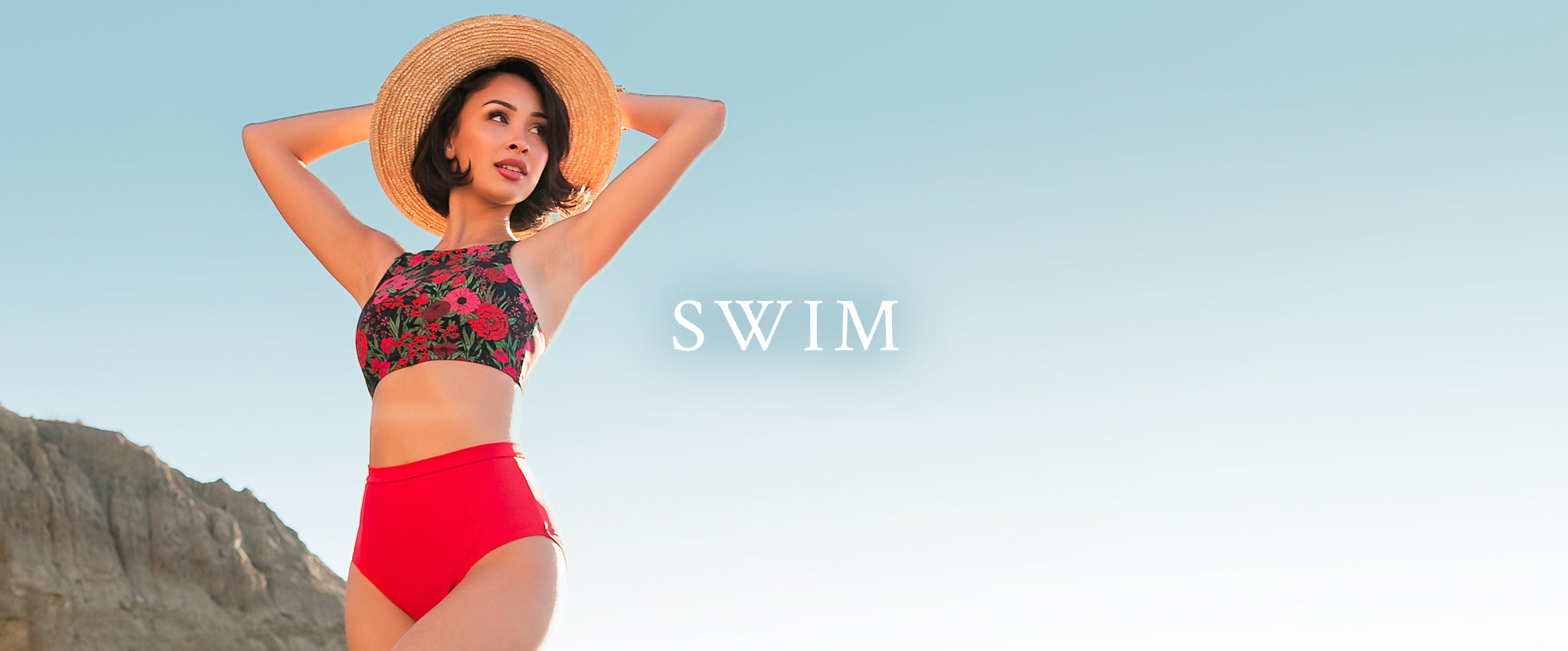 Woman in a two piece swimsuit with floral print on the top and solid red bottoms. Shop swim.