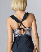 Woman in a one-piece swimsuit with a black & white gingham top and solid black lower half.