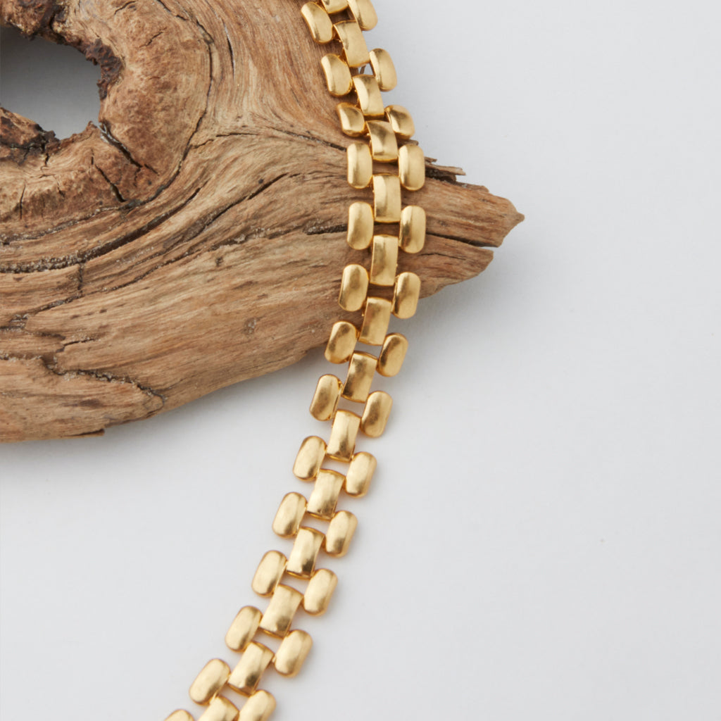 A chain necklace over some wood. 
