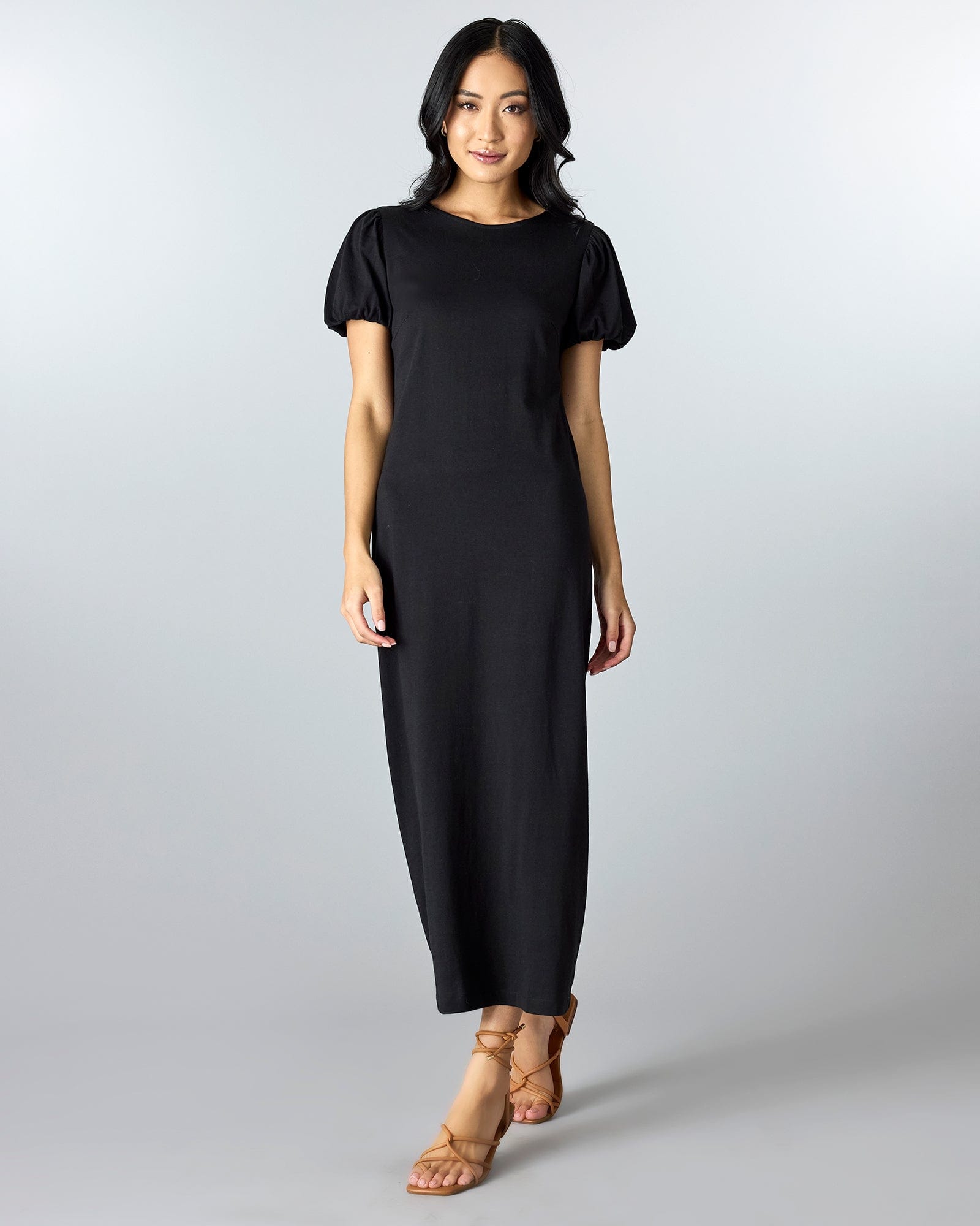 Woman in a black short sleeved, maxi sheath dress.