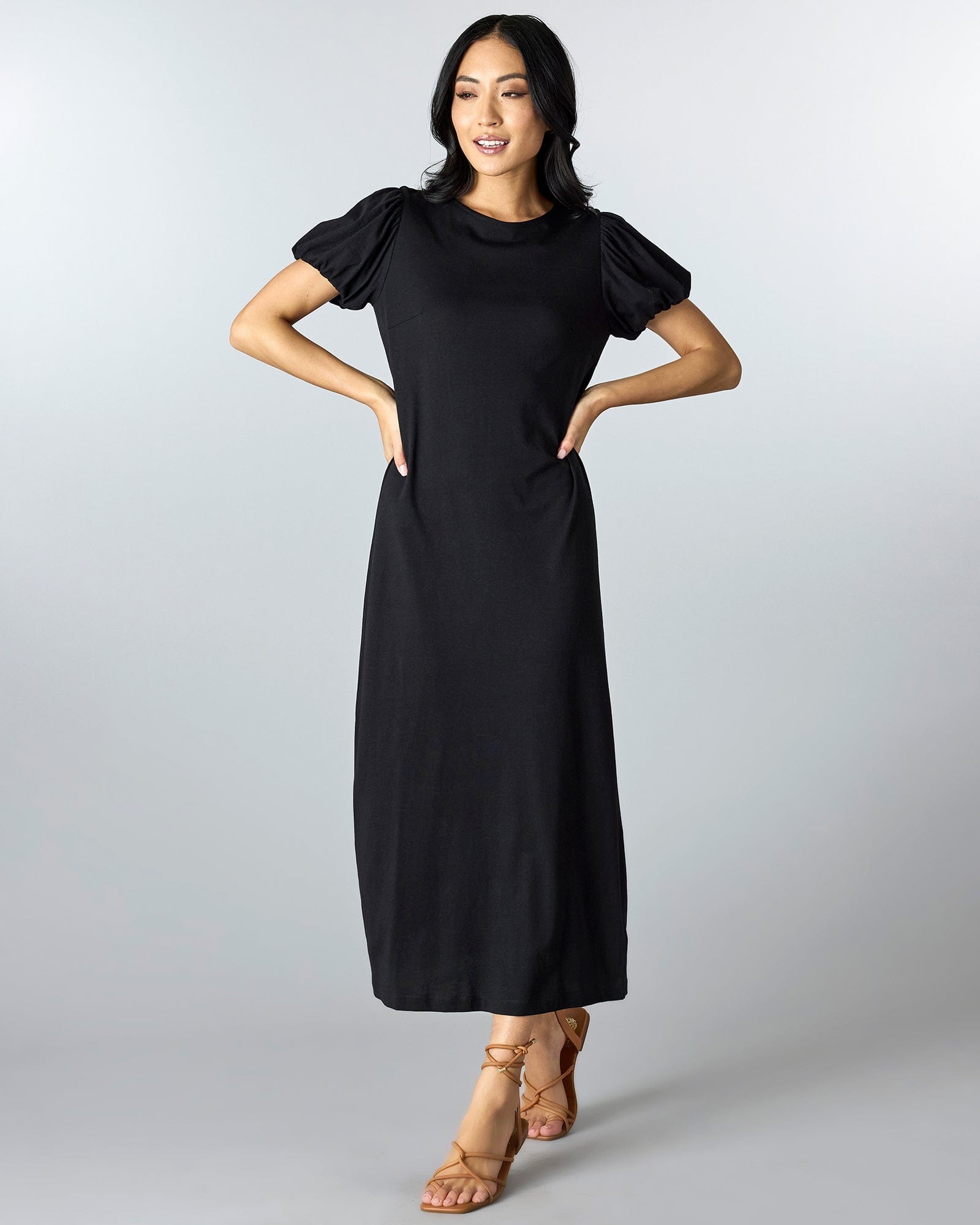 Woman in a black short sleeved, maxi sheath dress.