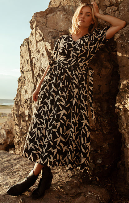 A women in a black and white dress on a rock. Shop dresses.
