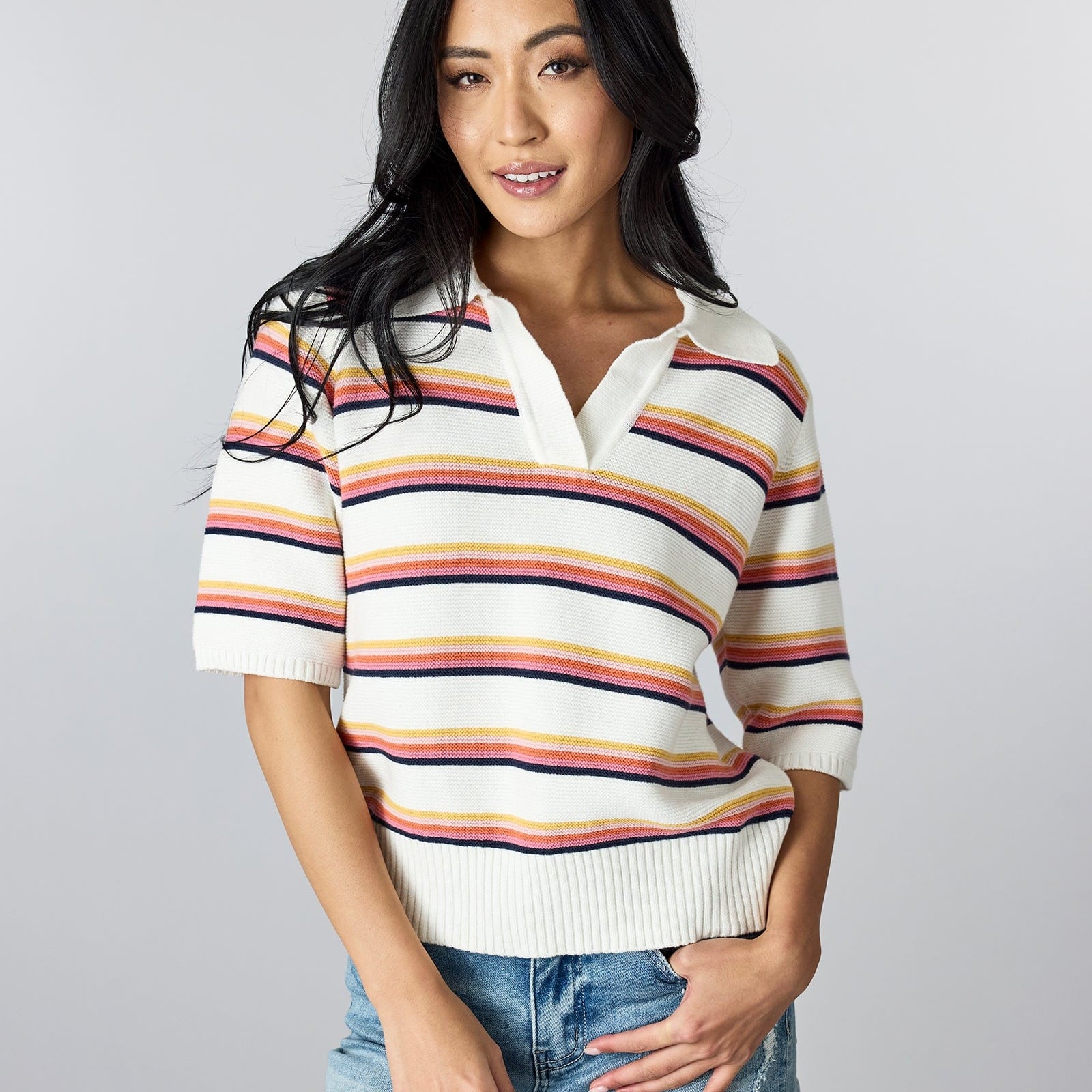 Woman in a half-sleeved, rainbow striped sweater with v-neck and collar.