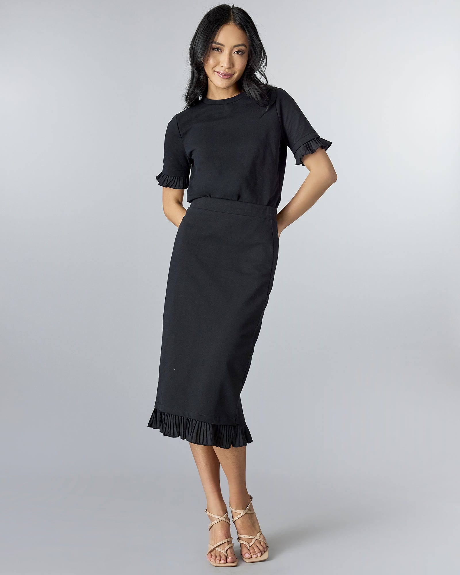 Woman in a black pencil skirt with ruffle at bottom.