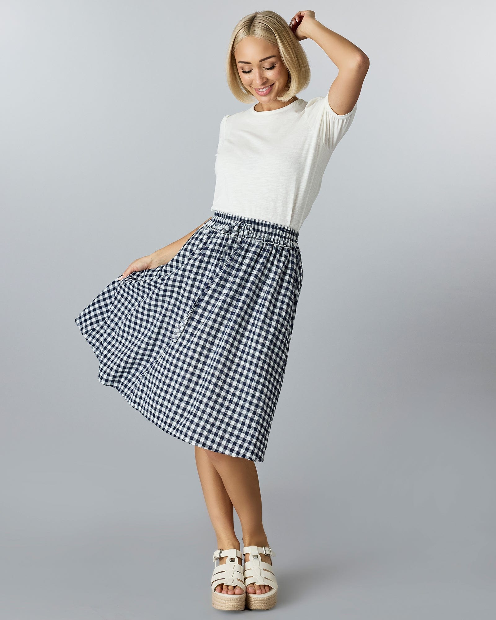 Woman in a gingham, midi-length skirt.