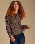 Woman in a blue and orange printed blouse with long sleeves