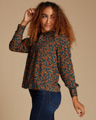 Woman in a blue and orange printed blouse with long sleeves