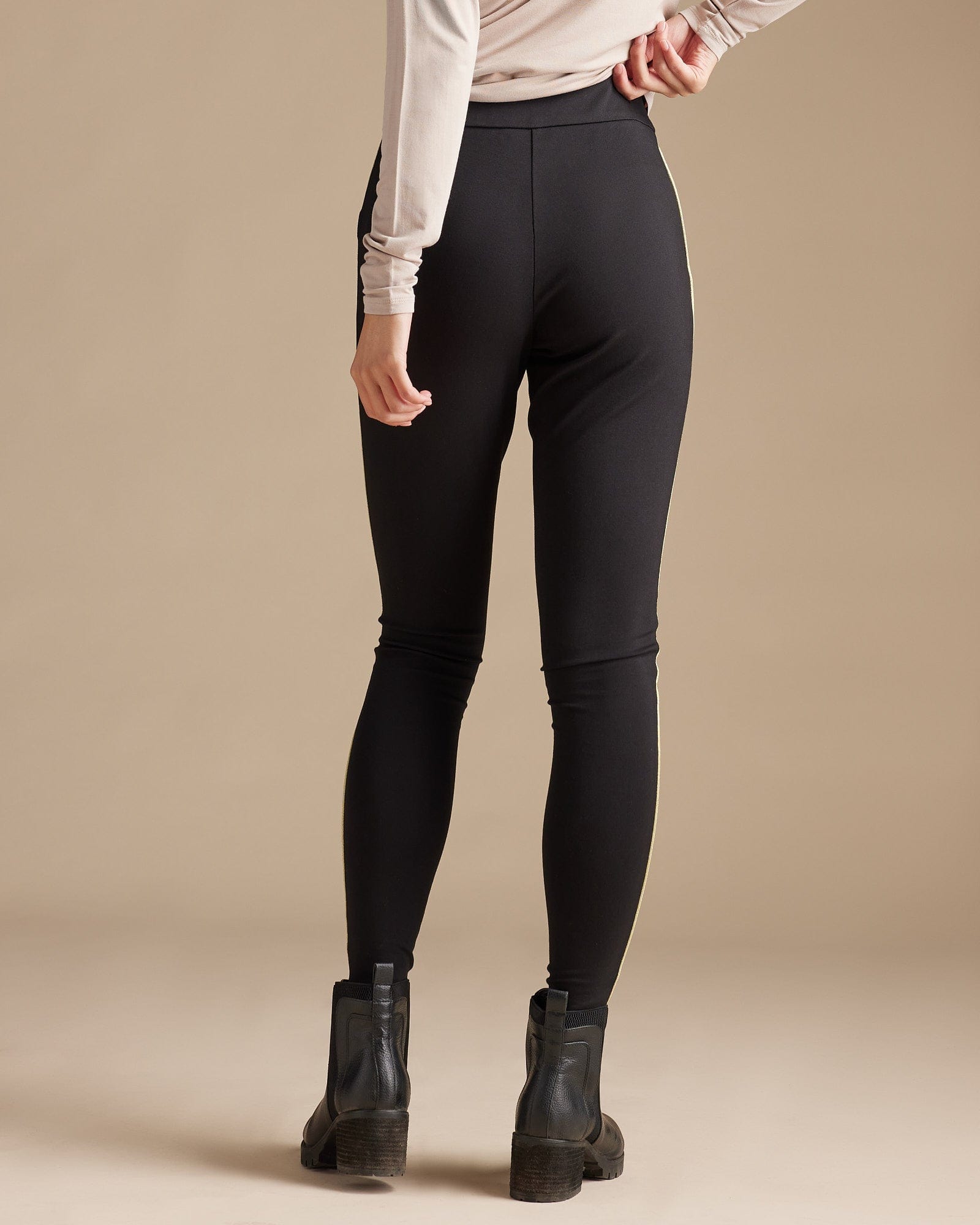 Woman in black leggings with gold piping along sides