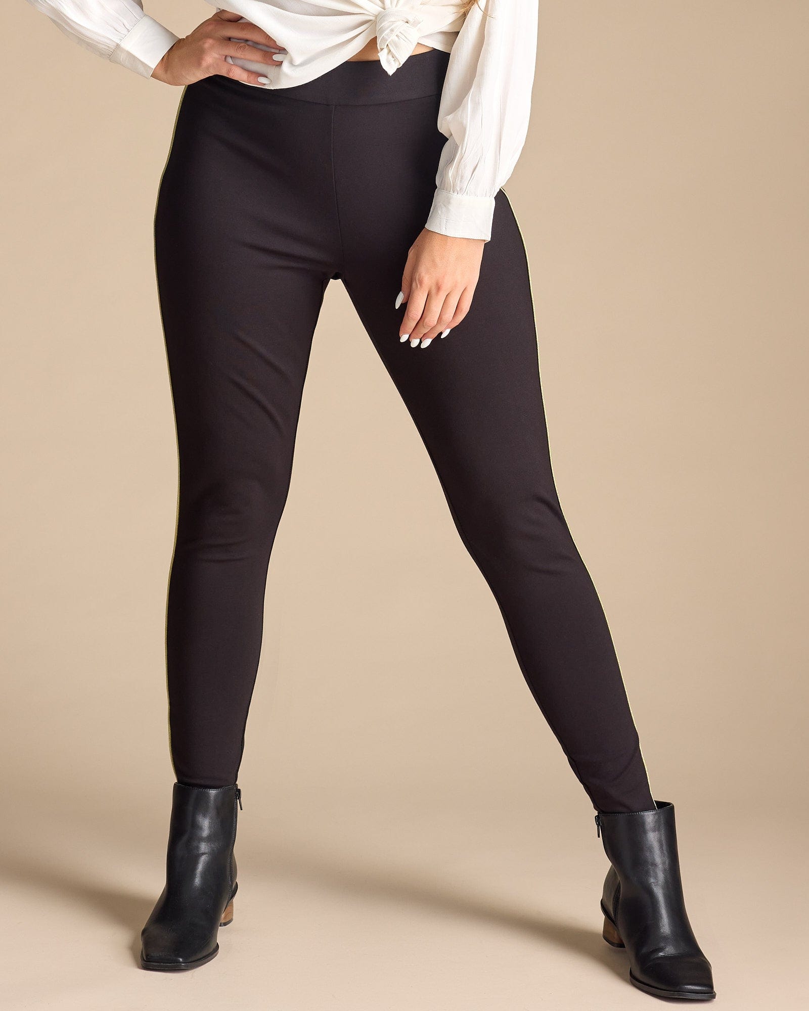 Woman in black leggings with gold piping along sides