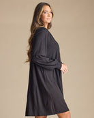 Woman in a long sleeve, knee-length, black dress with beaded front