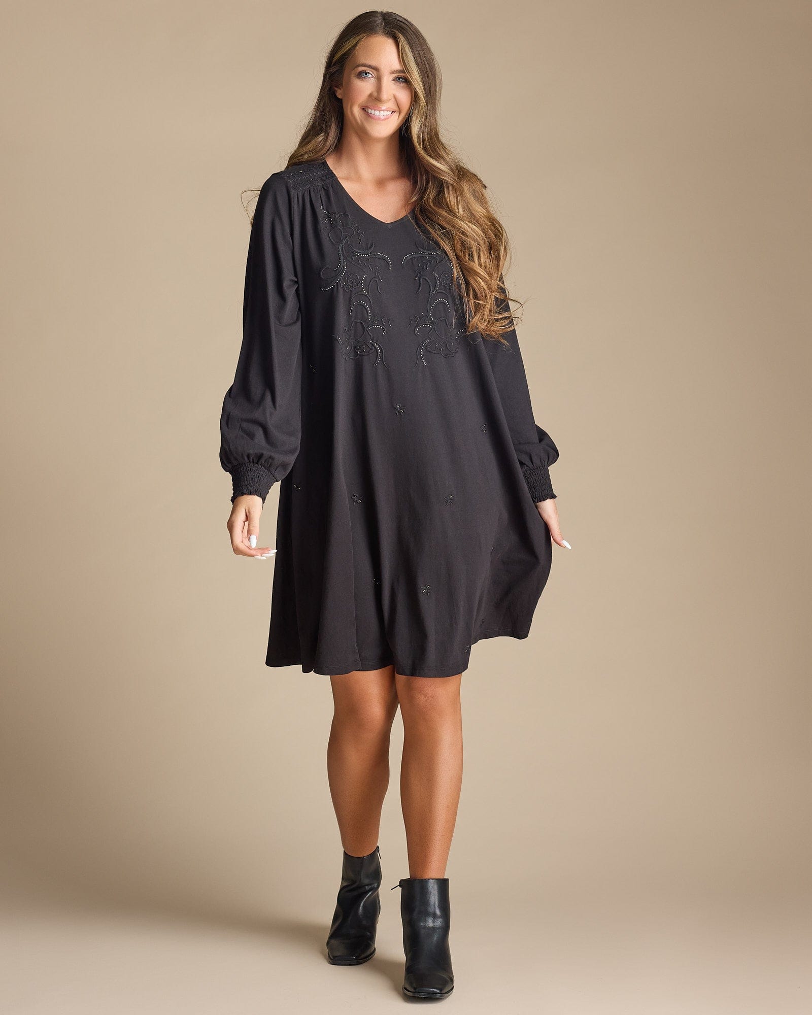 Woman in a long sleeve, knee-length, black dress with beaded front