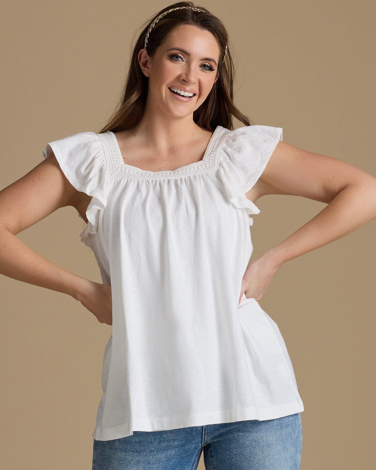 Woman in a white top with a square neckline and flutter sleeves