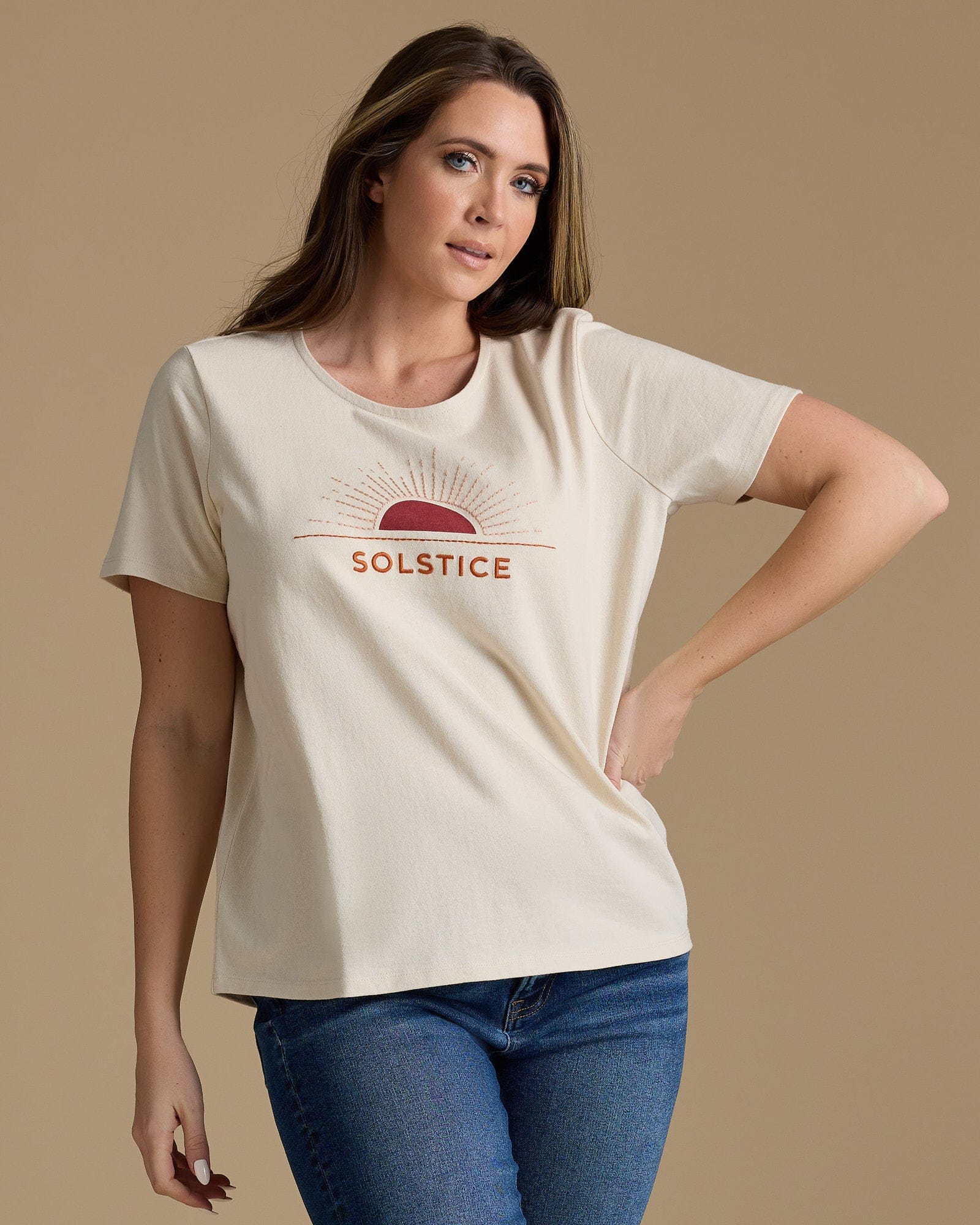 Woman in a tan graphic tee that says "solstice"