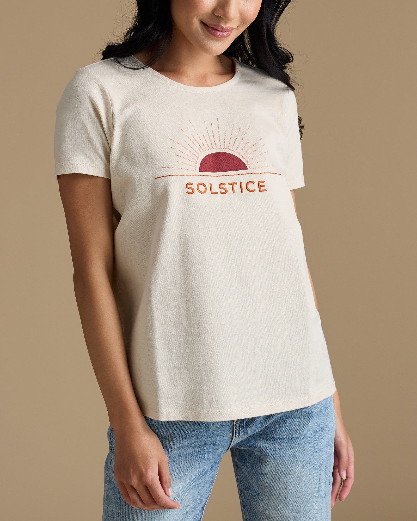 Woman in a tan graphic tee that says "solstice"