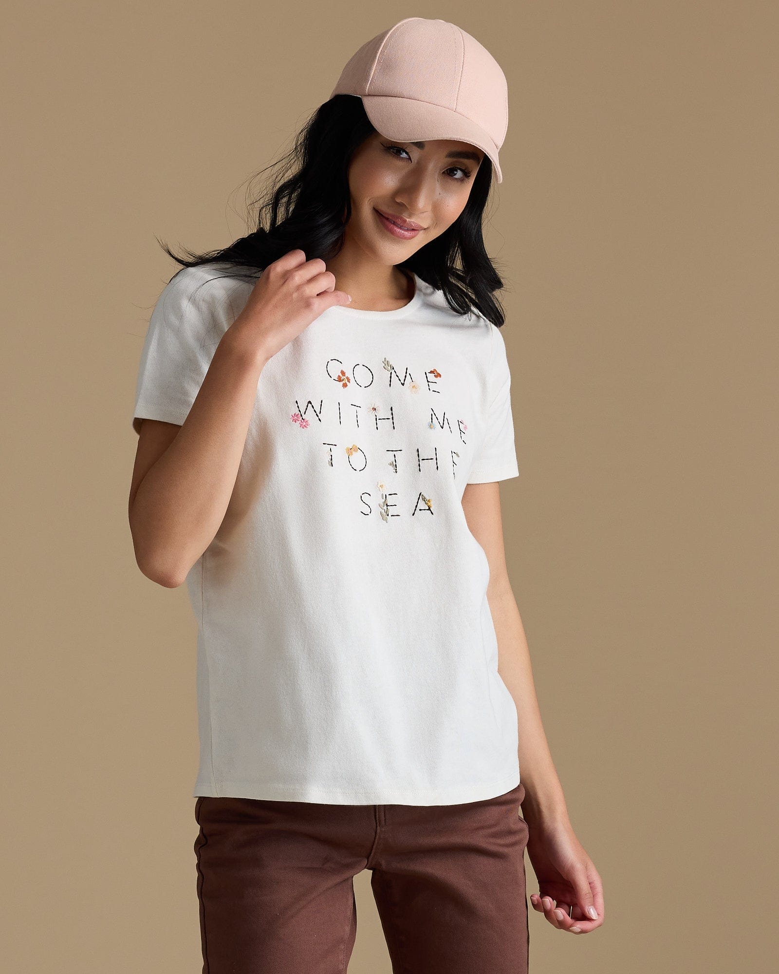 Woman in a white graphic tee that says "ccome with me to the sea"