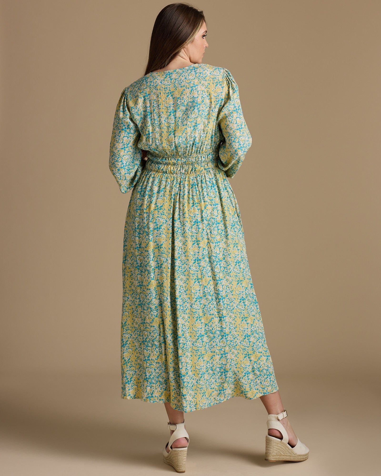 Woman in a long sleeve, maxi length, yellow and green floral print dress