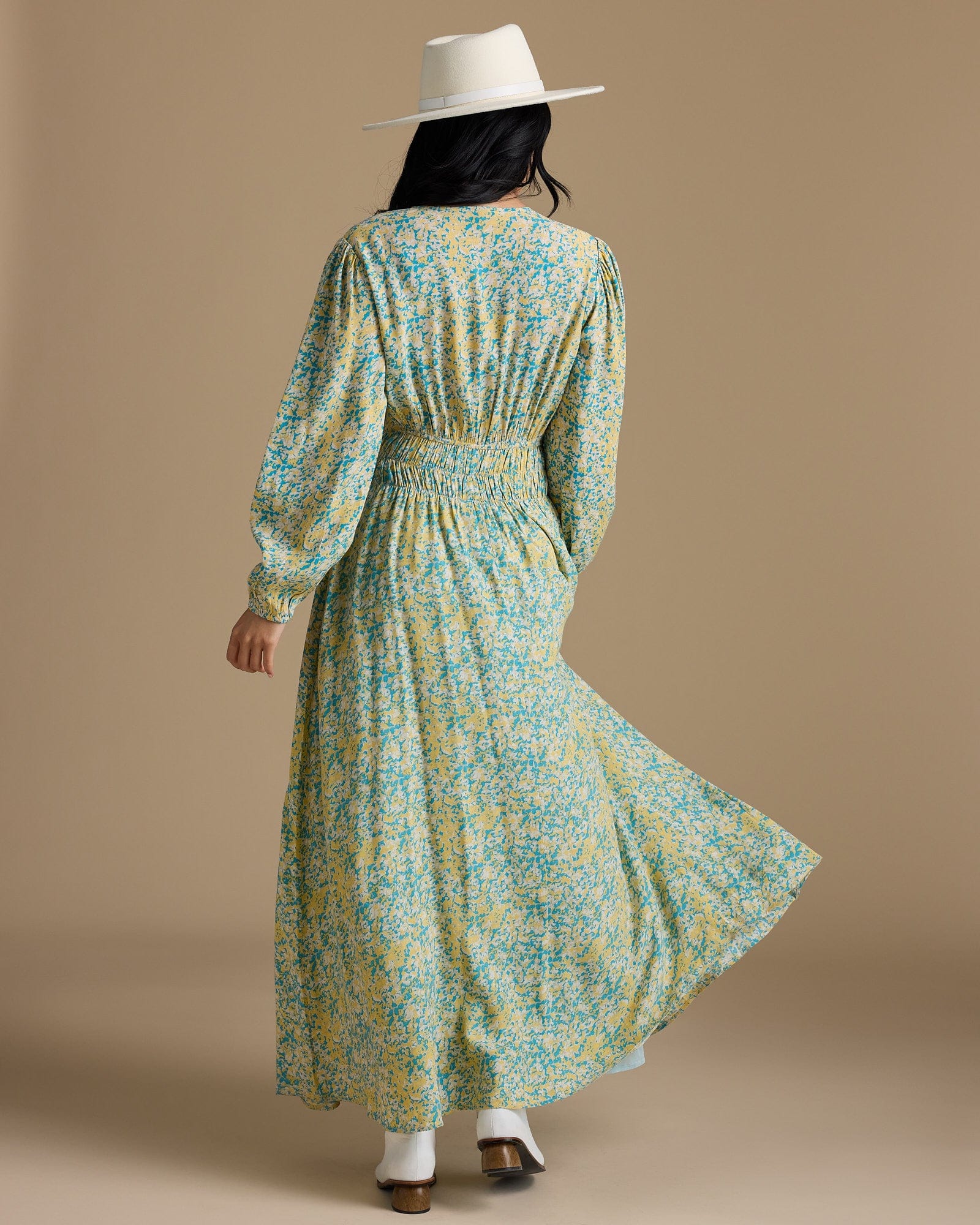 Woman in a long sleeve, maxi length, yellow and green floral print dress