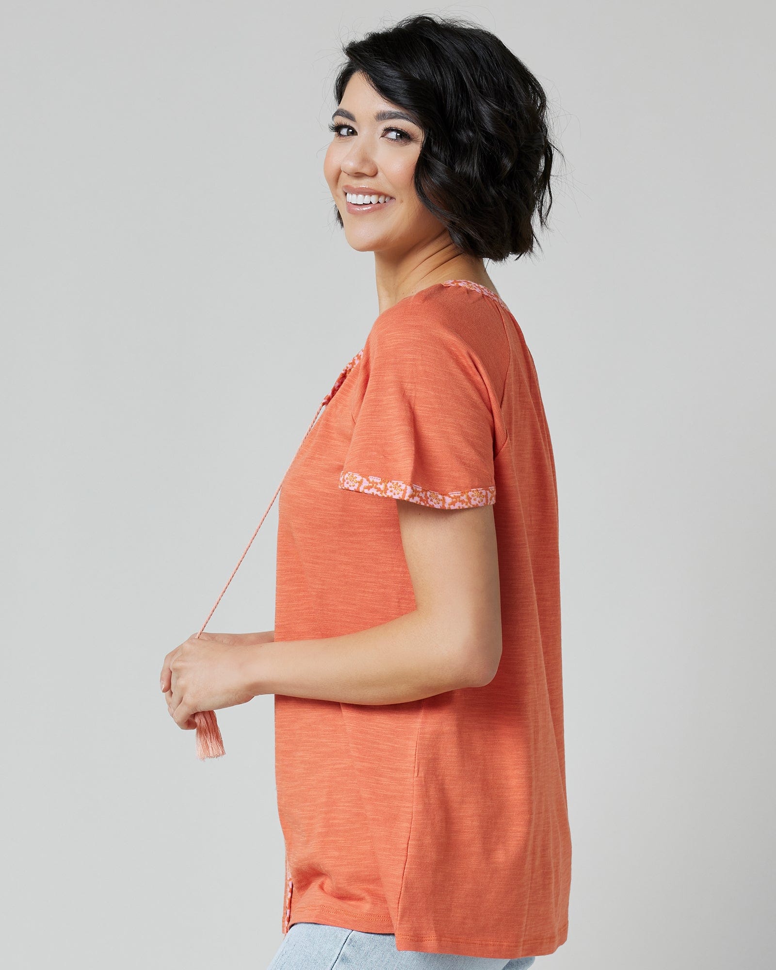 Woman in an orange top with short sleeves and buttons down the front