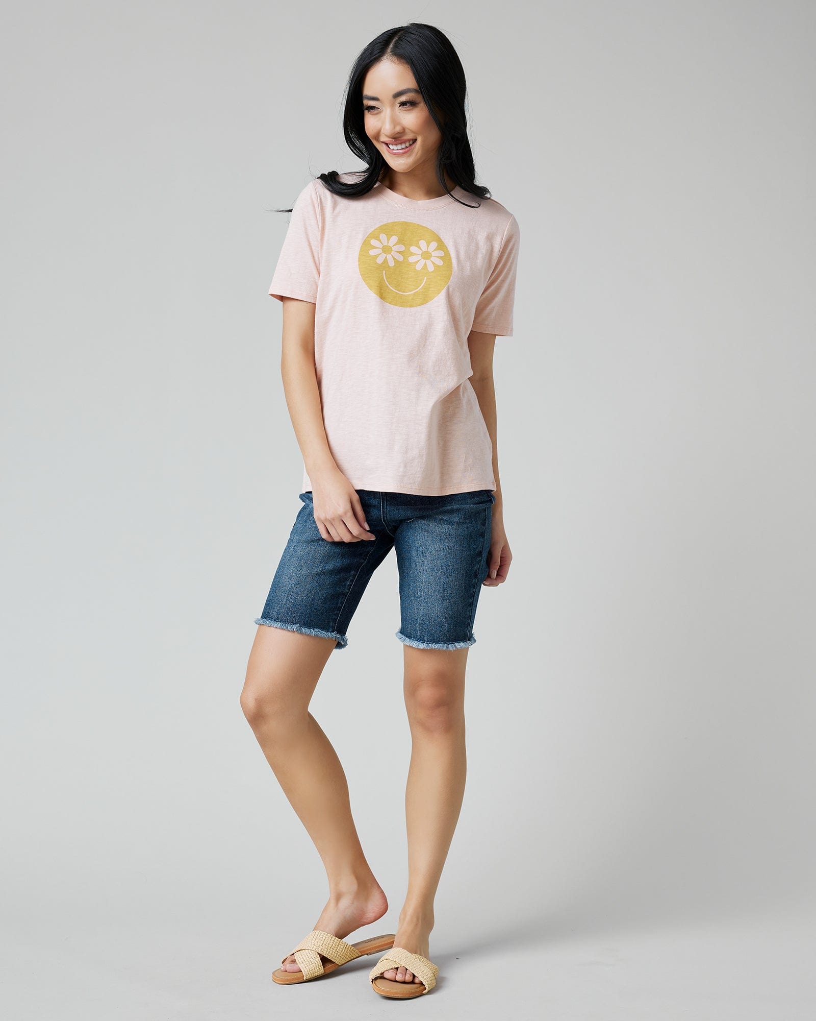 Woman in a pink graphic tee with a smiley face on front