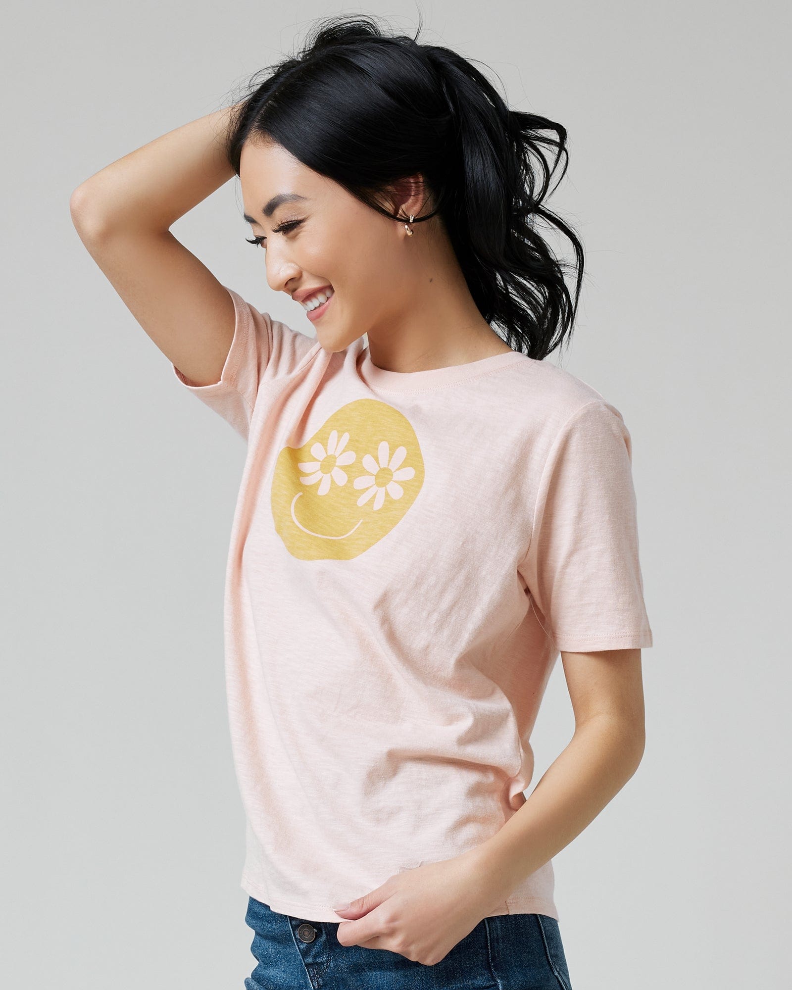 Woman in a pink graphic tee with a smiley face on front