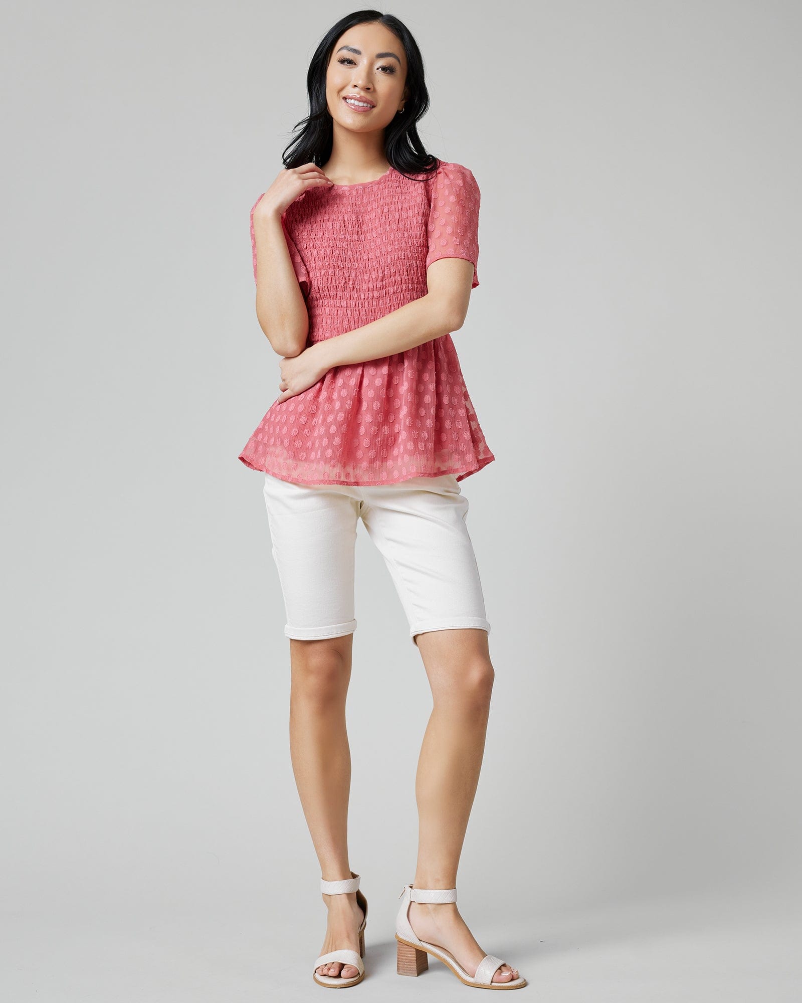 Woman in a pink peplum blouse with short sleeves, smocking and polka dots