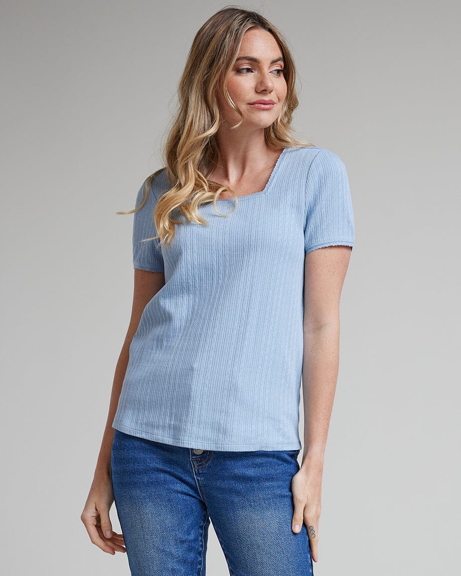 Woman in a blue top with short sleeves and a square neckline