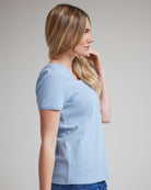 Woman in a blue top with short sleeves and a square neckline