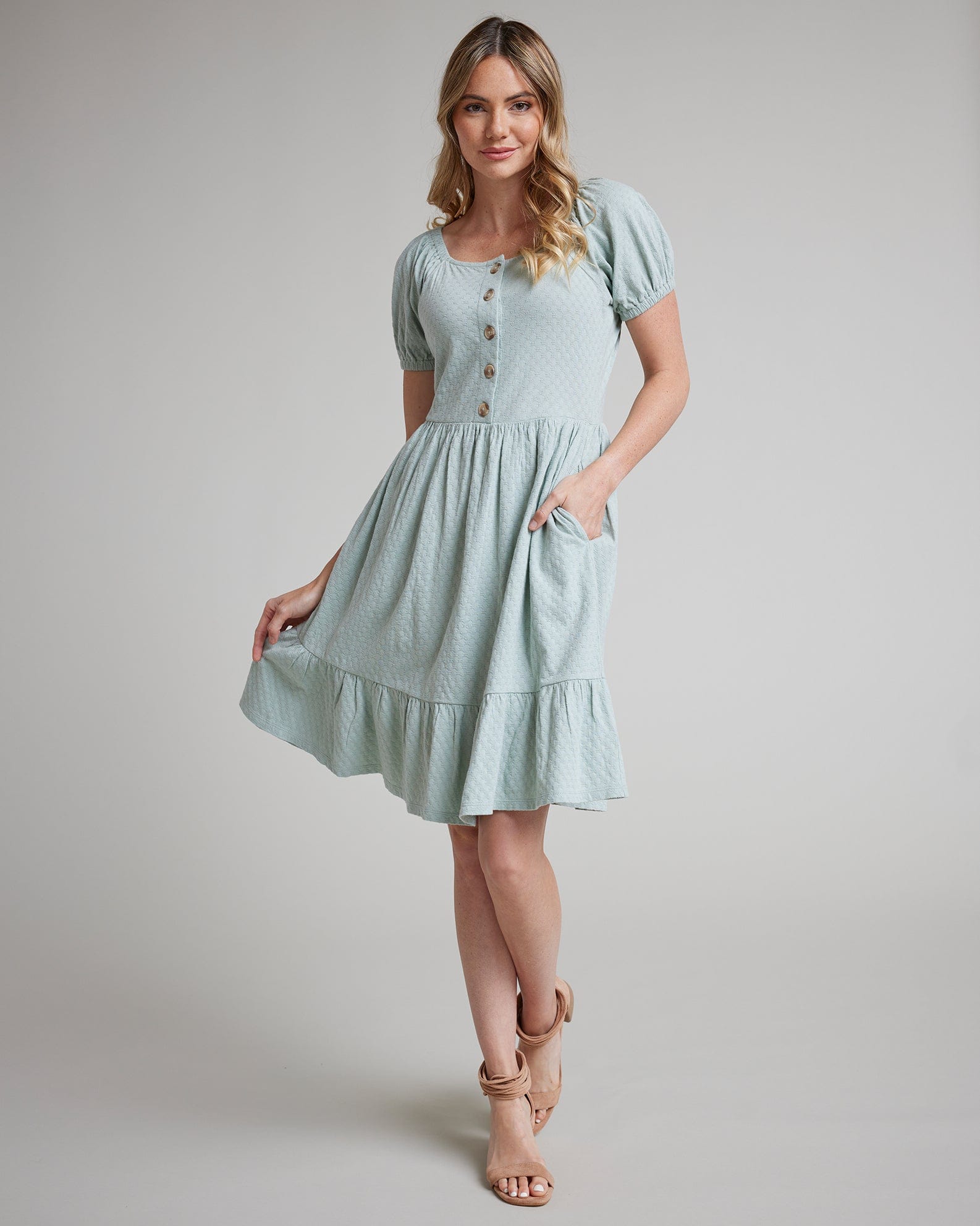 Woman in a short sleeve, square neck, blue dress with buttons down the front