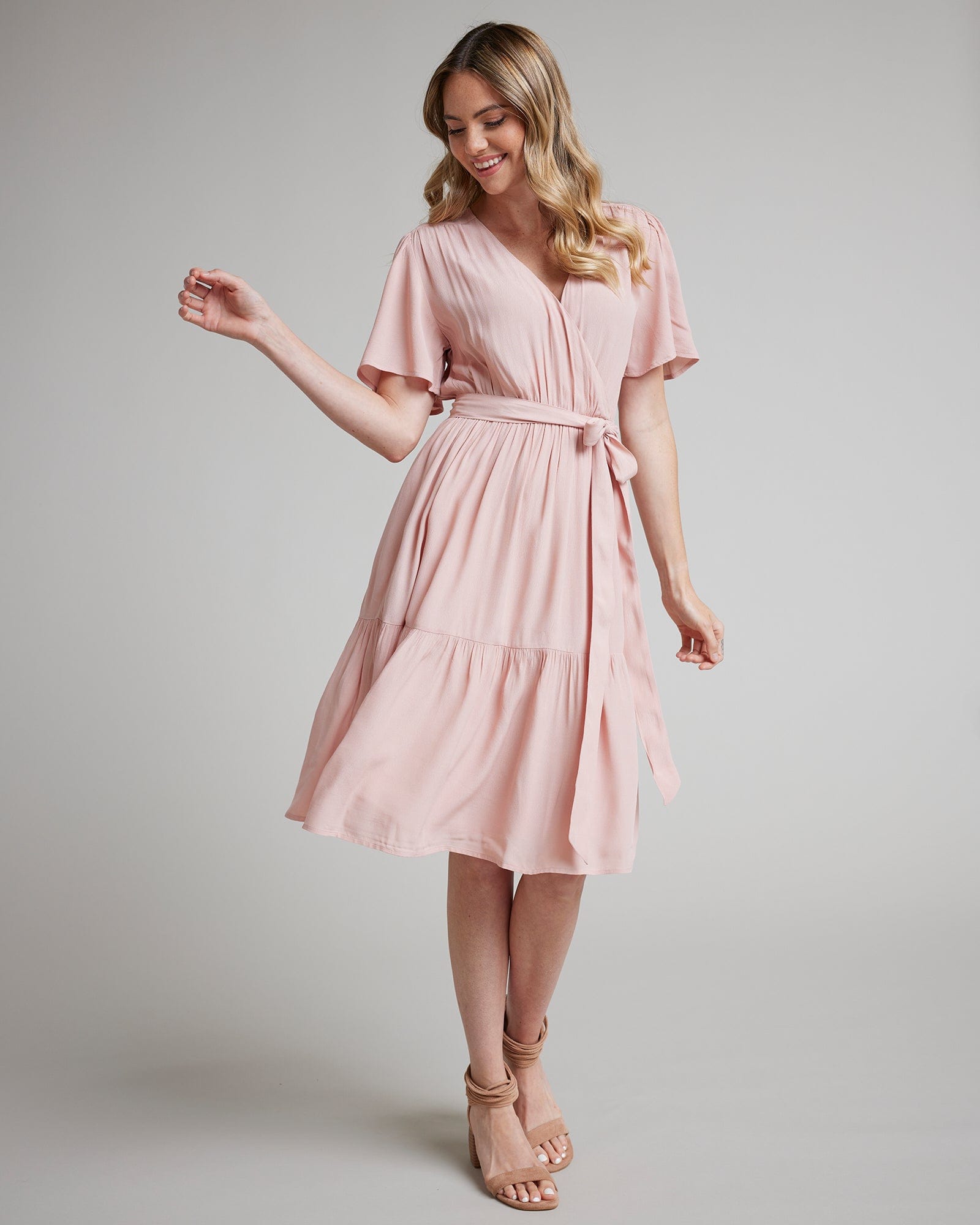 Woman in a short sleeve, knee-length, pink wrap dress