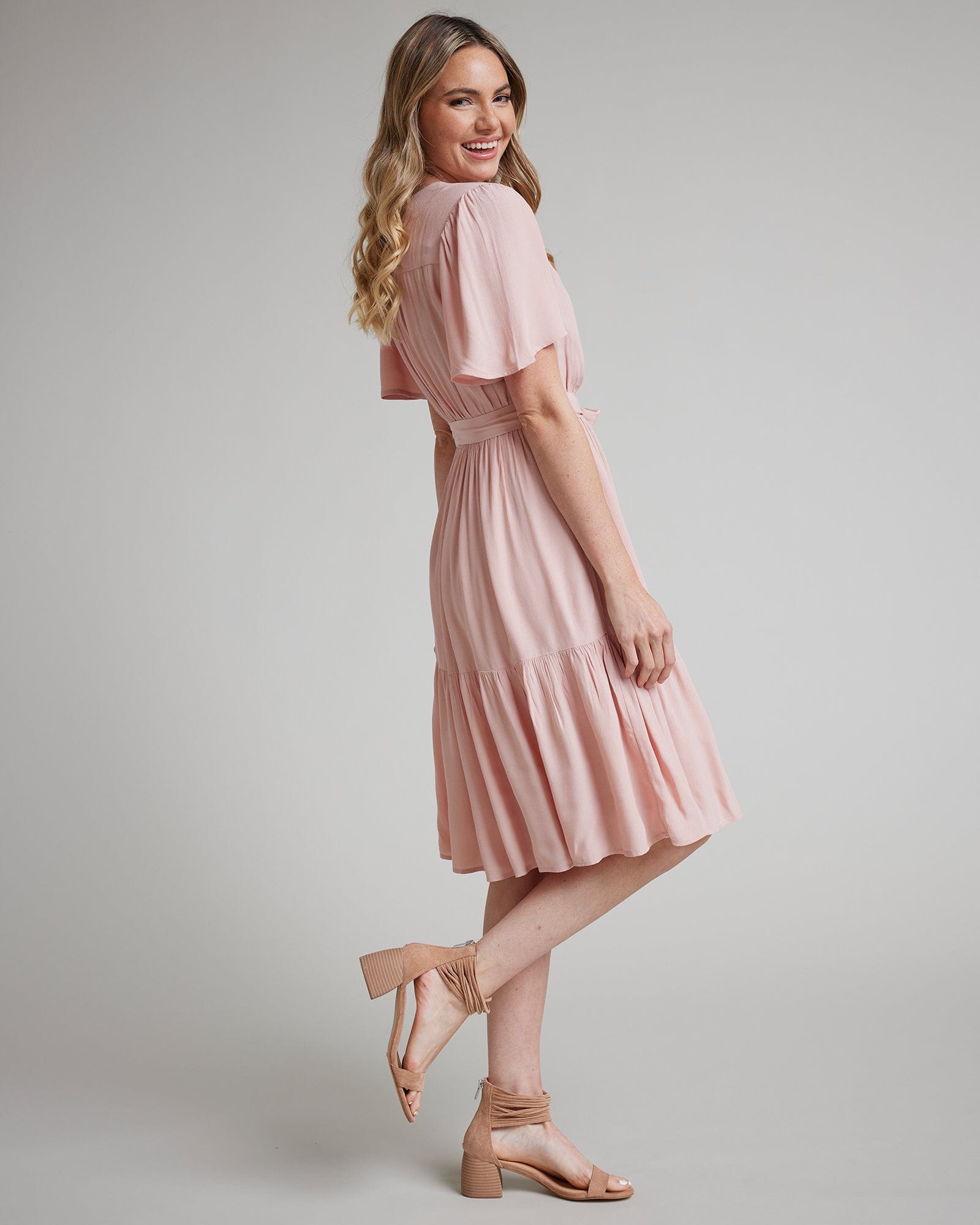 Woman in a short sleeve, knee-length, pink wrap dress