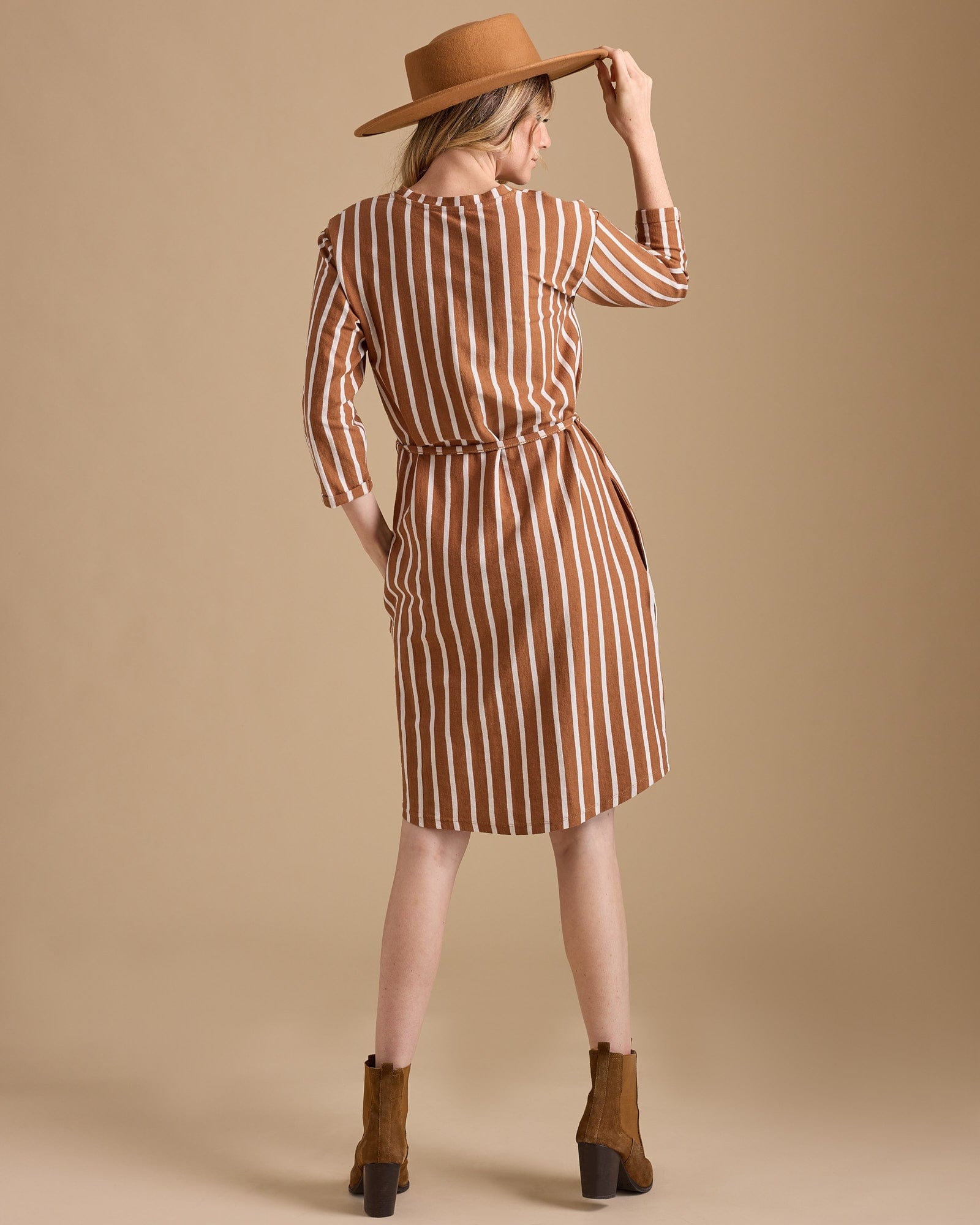 Woman in a 3/4 sleeve, knee-length, brown vertical stripe dress