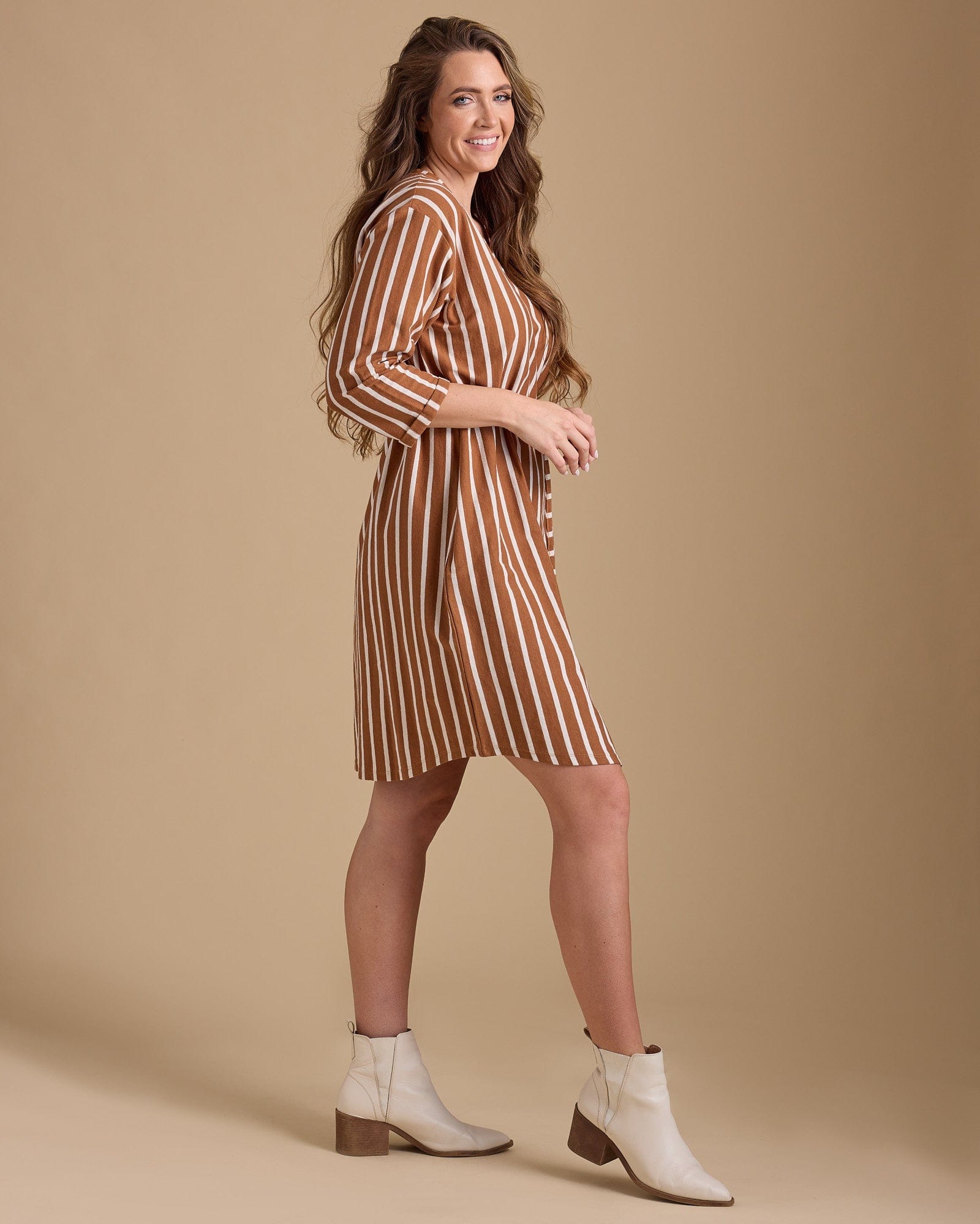 Woman in a 3/4 sleeve, knee-length, brown vertical stripe dress
