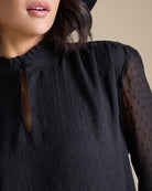 Woman in a dotted swiss blouse with long sleeves and a key-hole cutout
