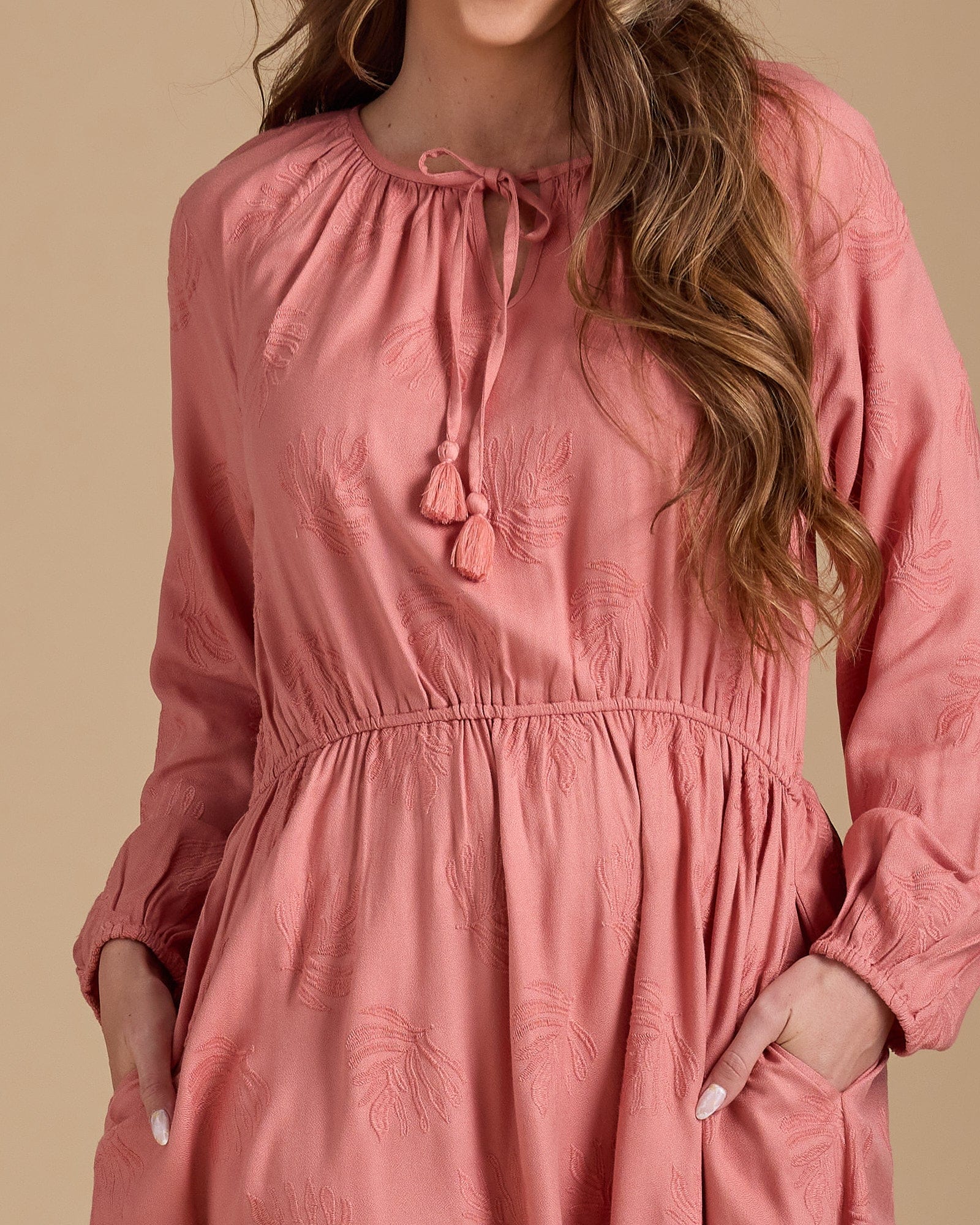 Woman in a long sleeve, knee-length pink dress with pockets