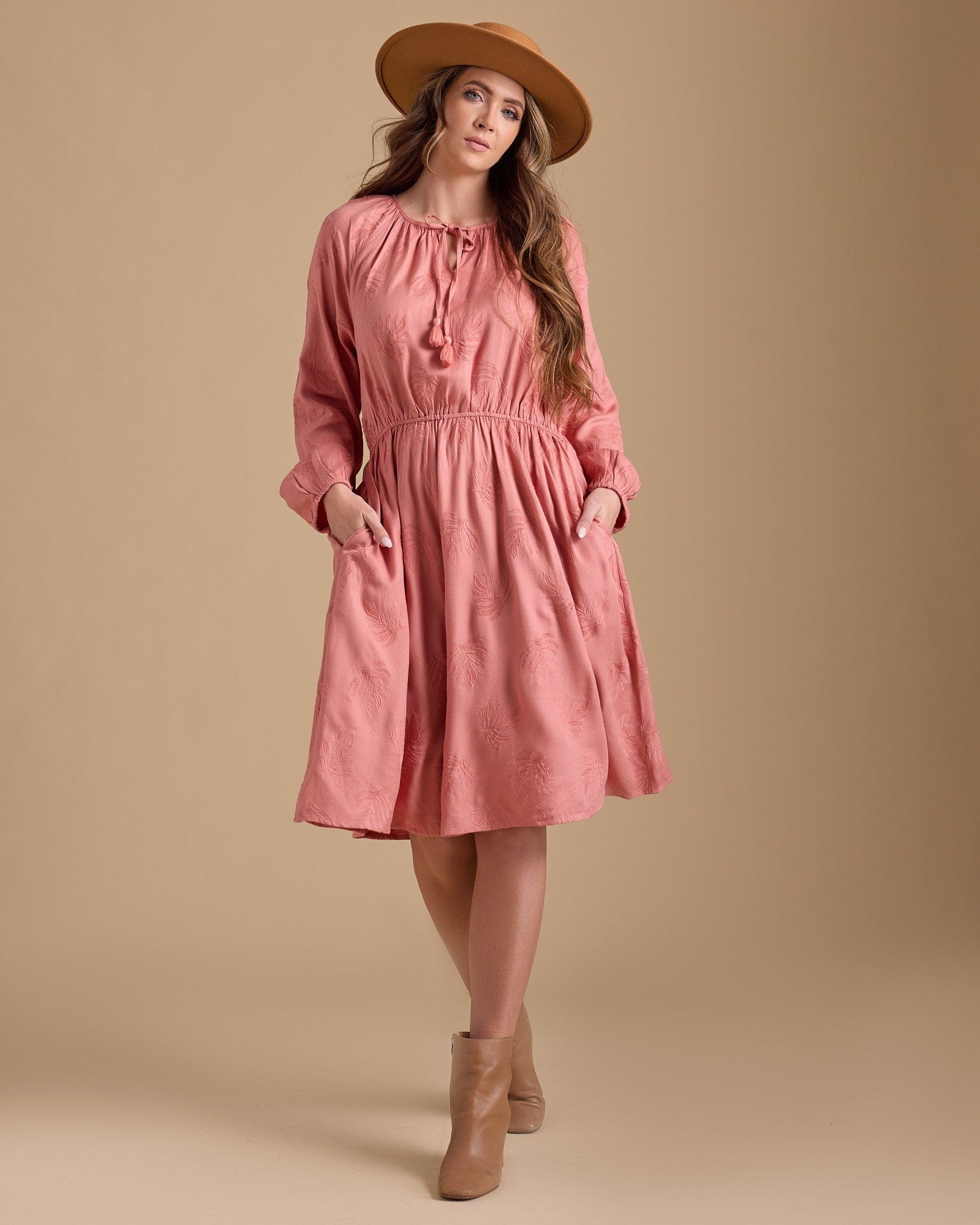 Woman in a long sleeve, knee-length pink dress with pockets
